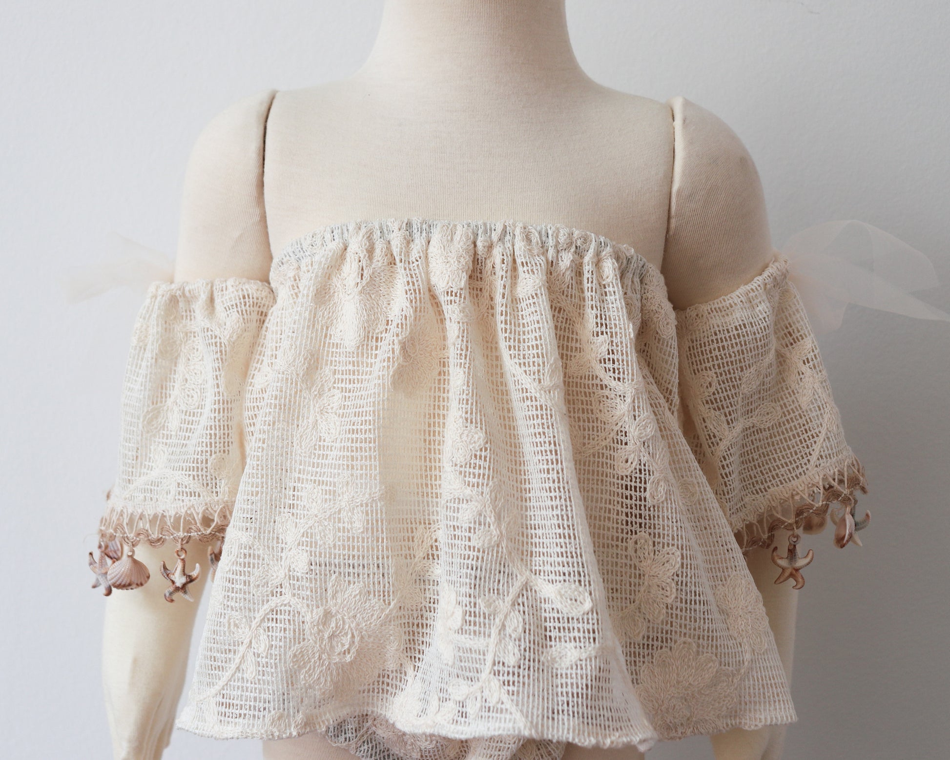 Boho-inspired toddler girl outfit laid flat: off-shoulder lace top and bloomer set