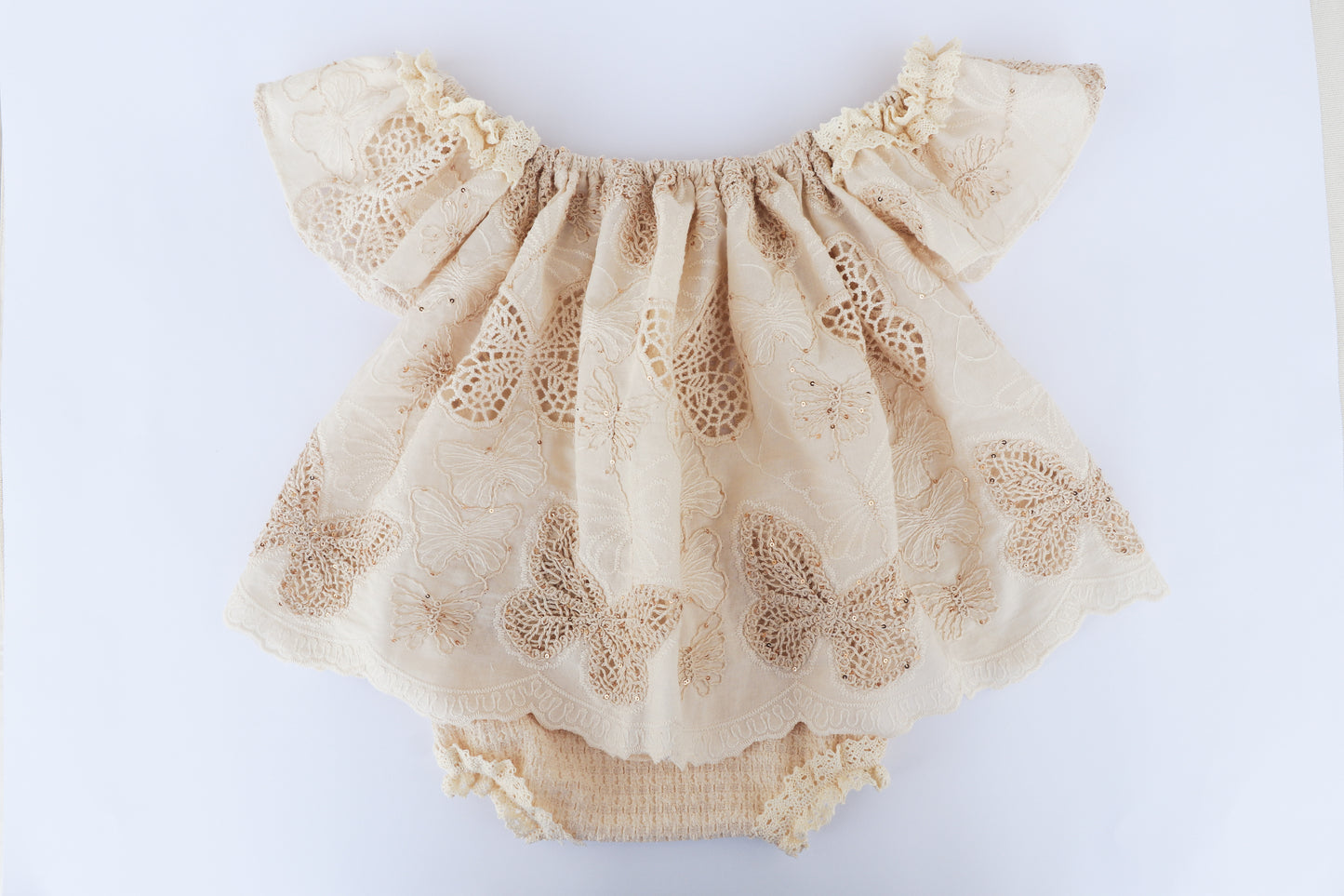Beige lace baby romper on a white background