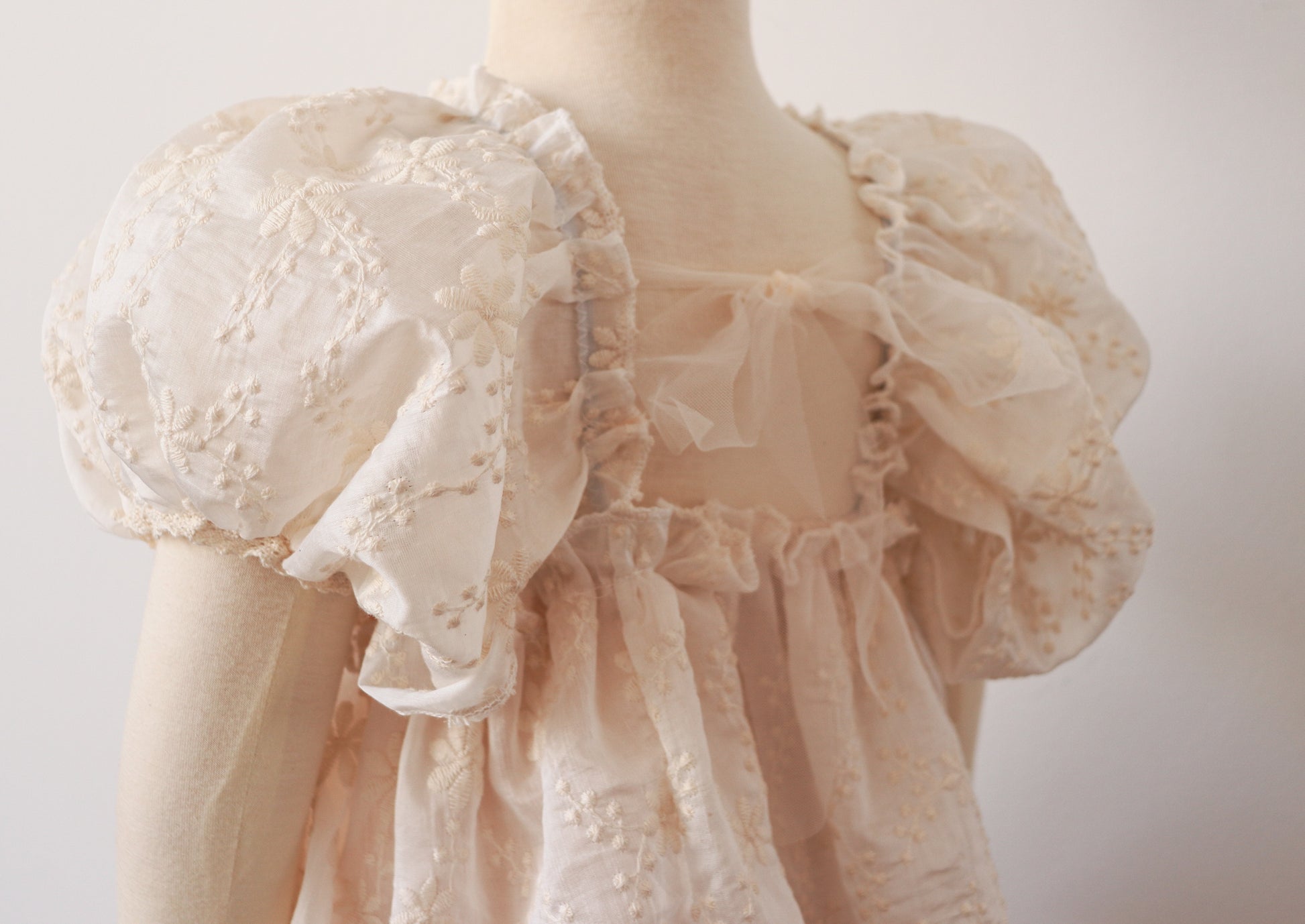 "Close-up of a beautiful beige embroidered chiffon dress with soft puffy sleeves and intricate lace, designed for special celebrations and outdoor sessions."