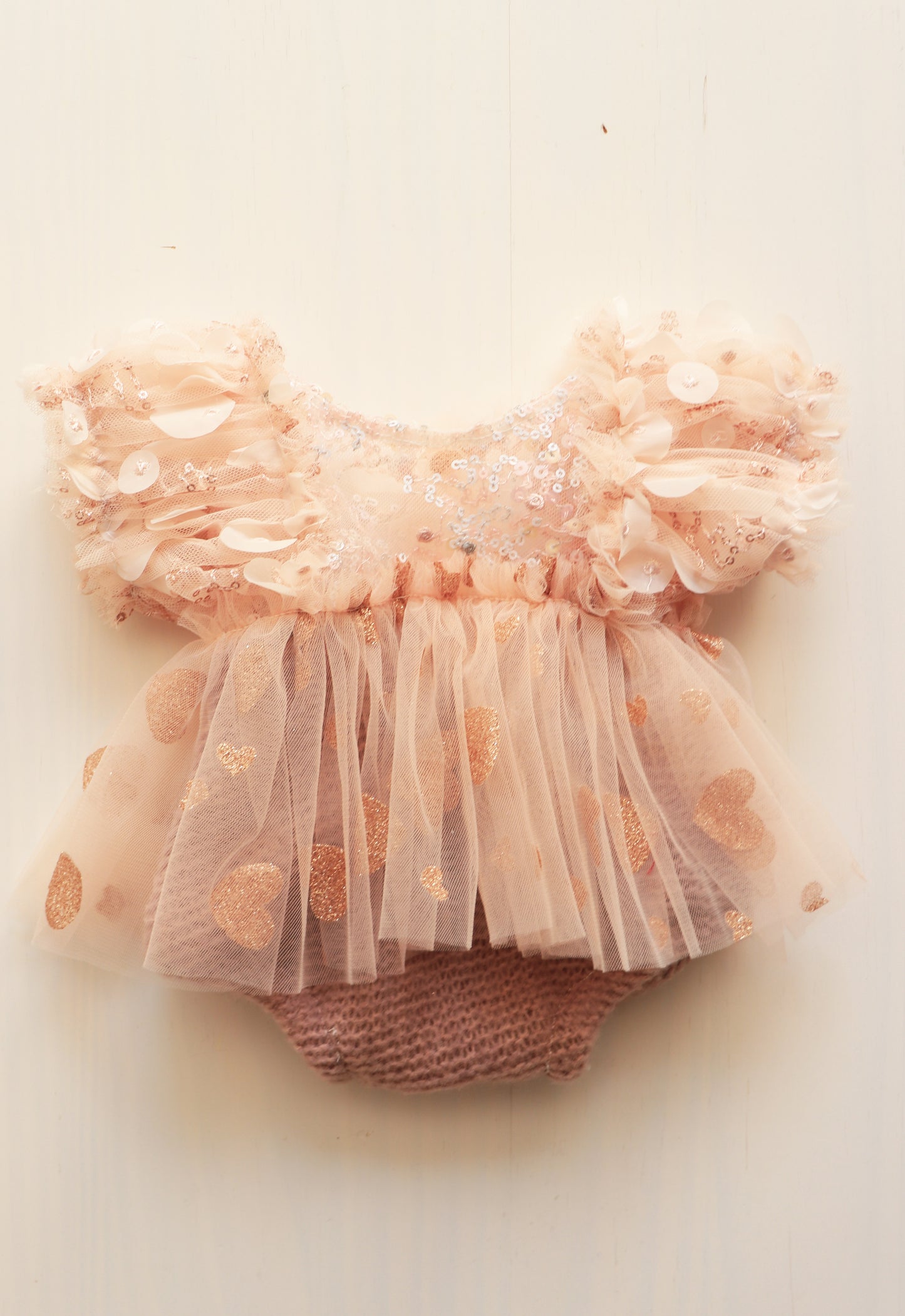 Newborn girl’s romper dress with pink pastel puffed sleeves, golden tulle skirt, and sequins bodice