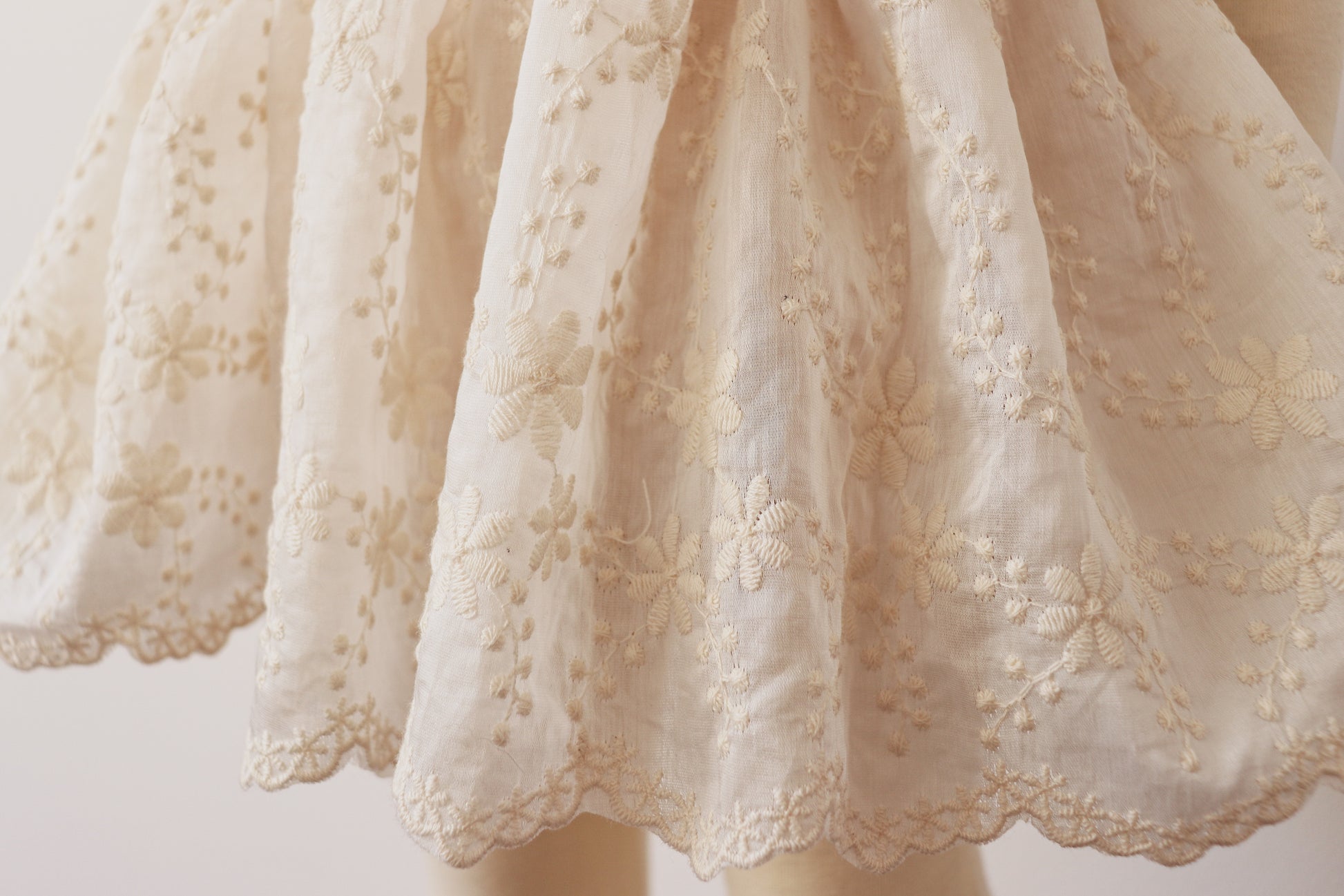 "Little girl wearing a dreamy beige chiffon dress with vintage lace bodice and puffy sleeves, capturing elegance and charm in a boho outdoor setting."