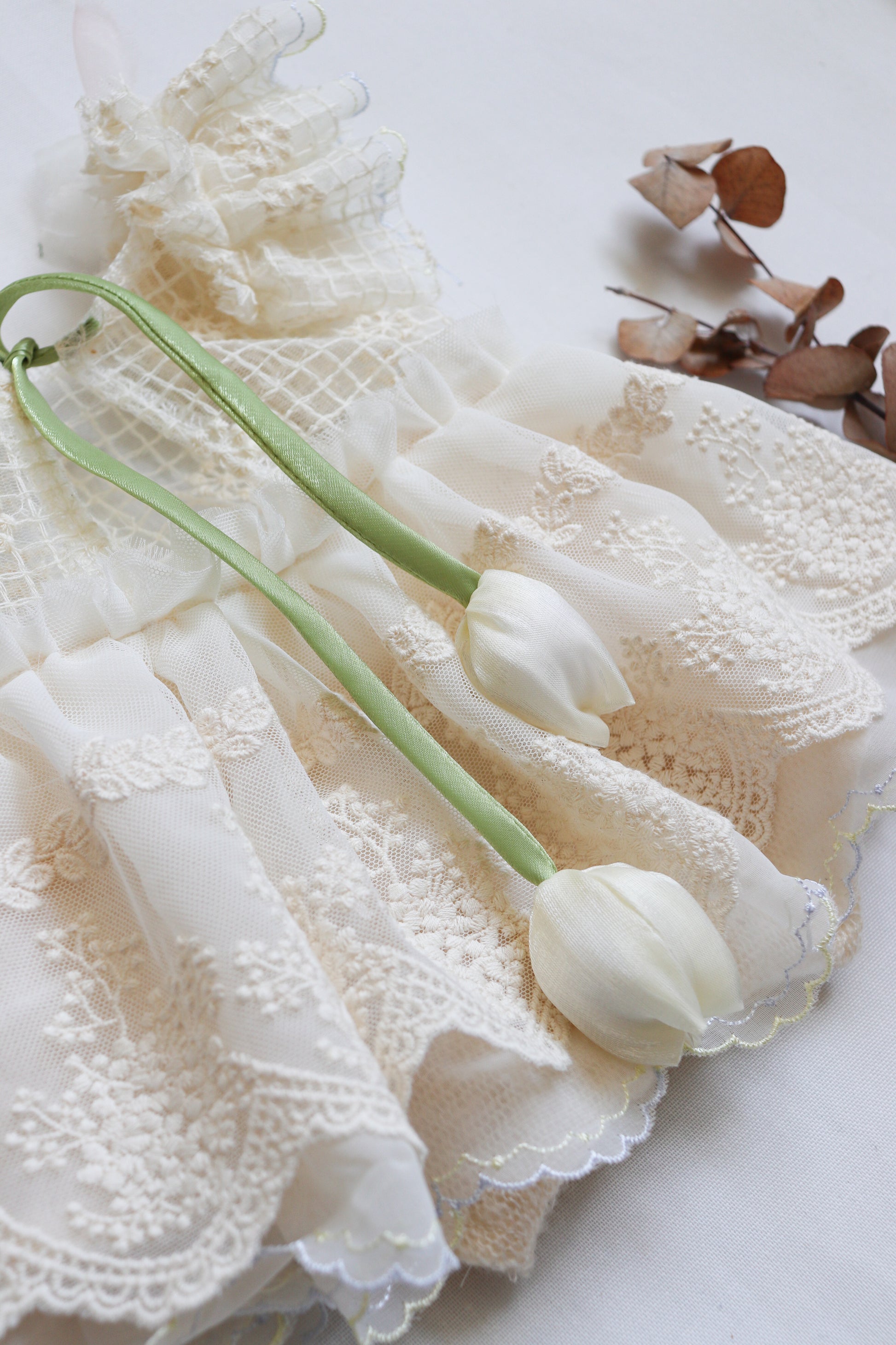 Vintage-inspired baby romper in soft ivory lace and chiffon, with tulip-style straps and ruffled bodice details