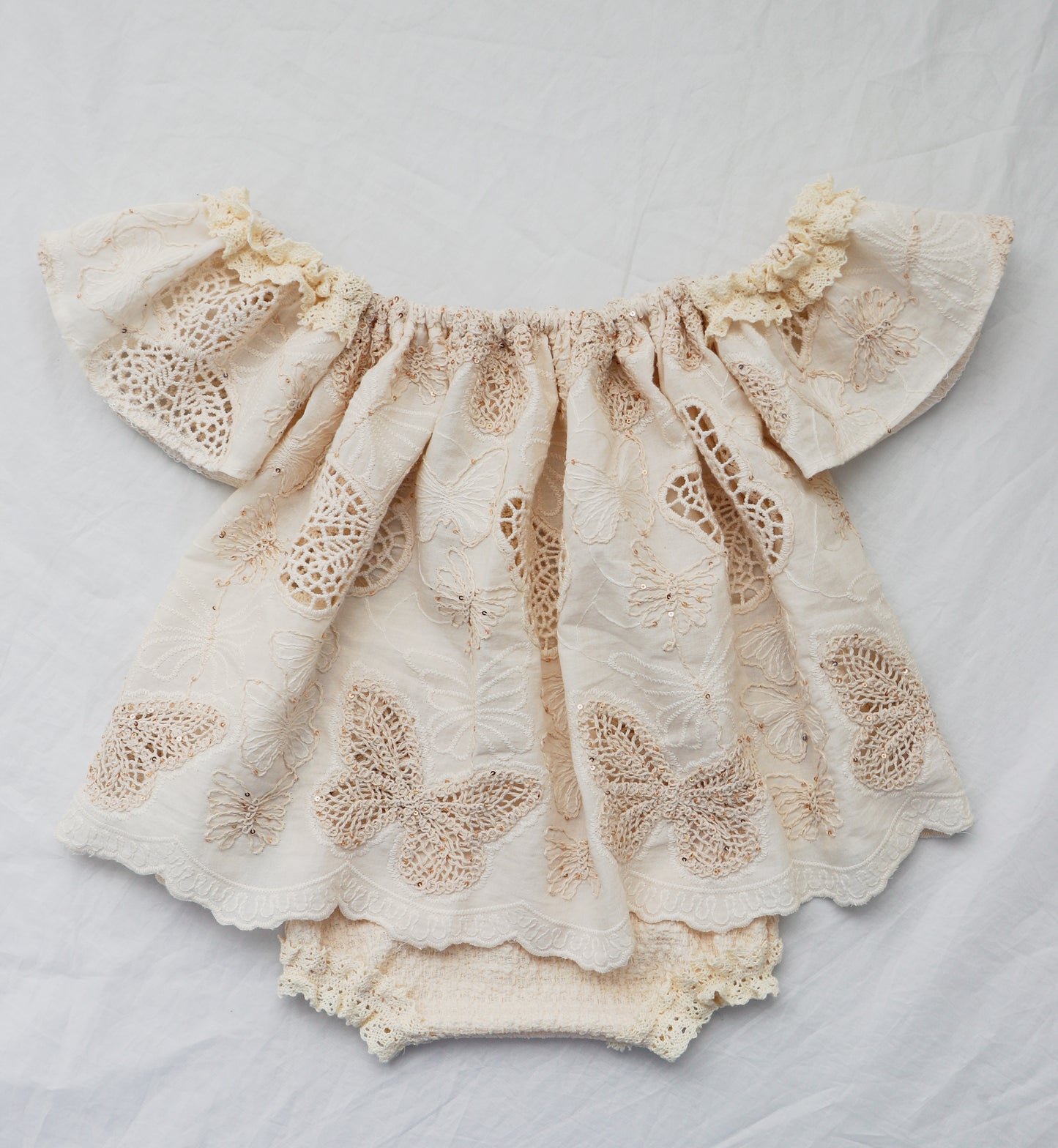 Beige cotton knit baby bloomer set with butterfly embroidery and off-shoulder top by Fleur Margot