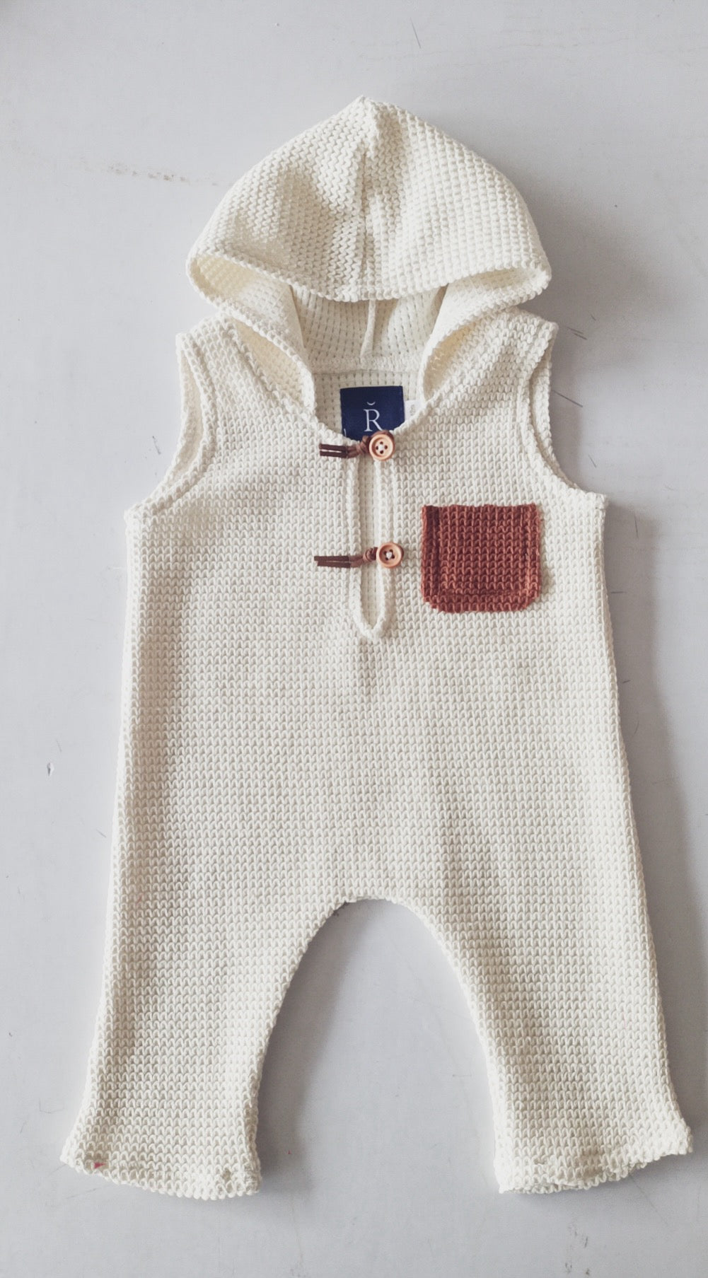 Cream knit sleeveless sitter romper for photoshoot with hood and brown front pocket