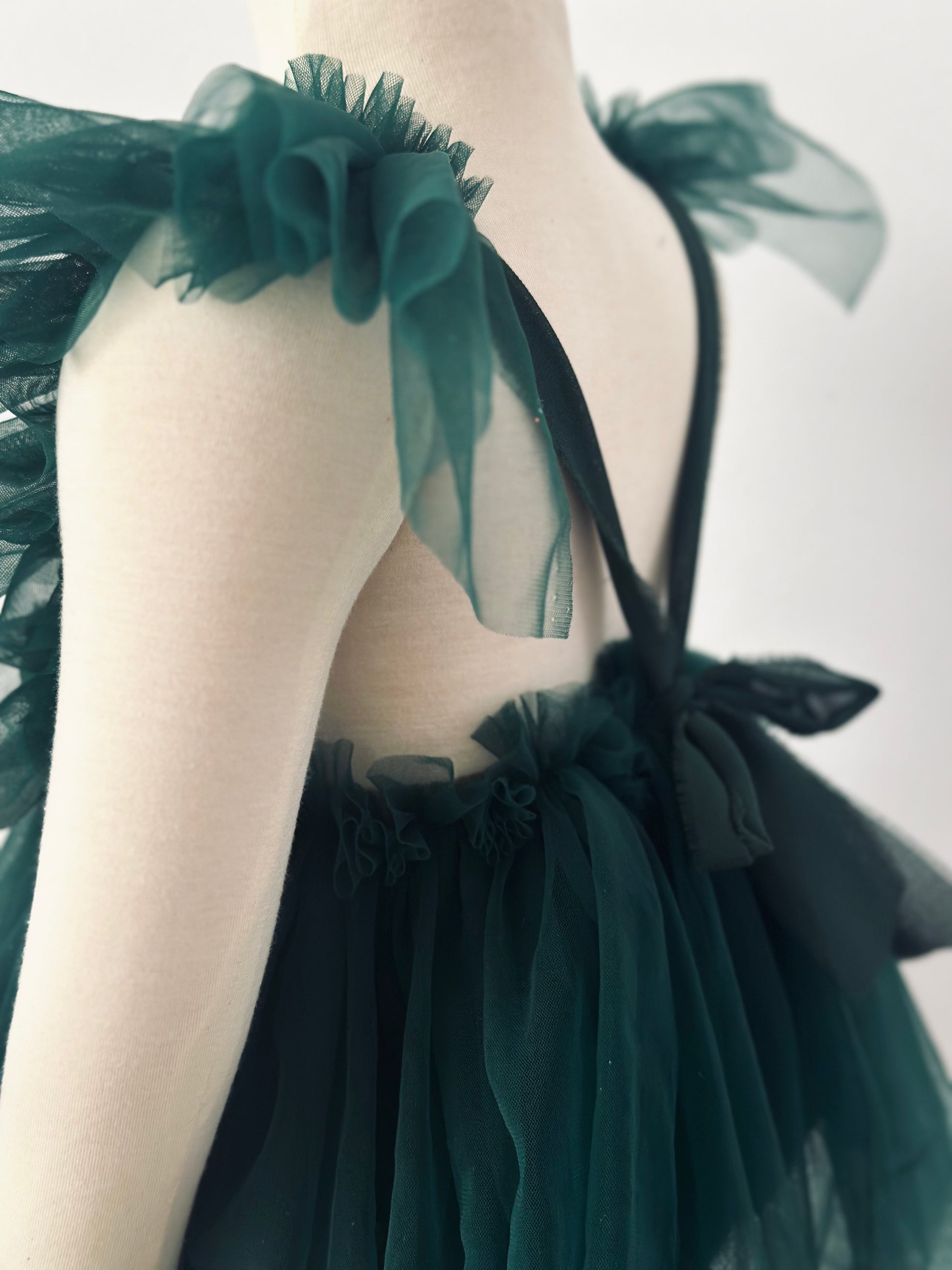 Evergreen girl dress photoshoot christmas session featuring dark green tulle dress with ruffled straps on mannequin