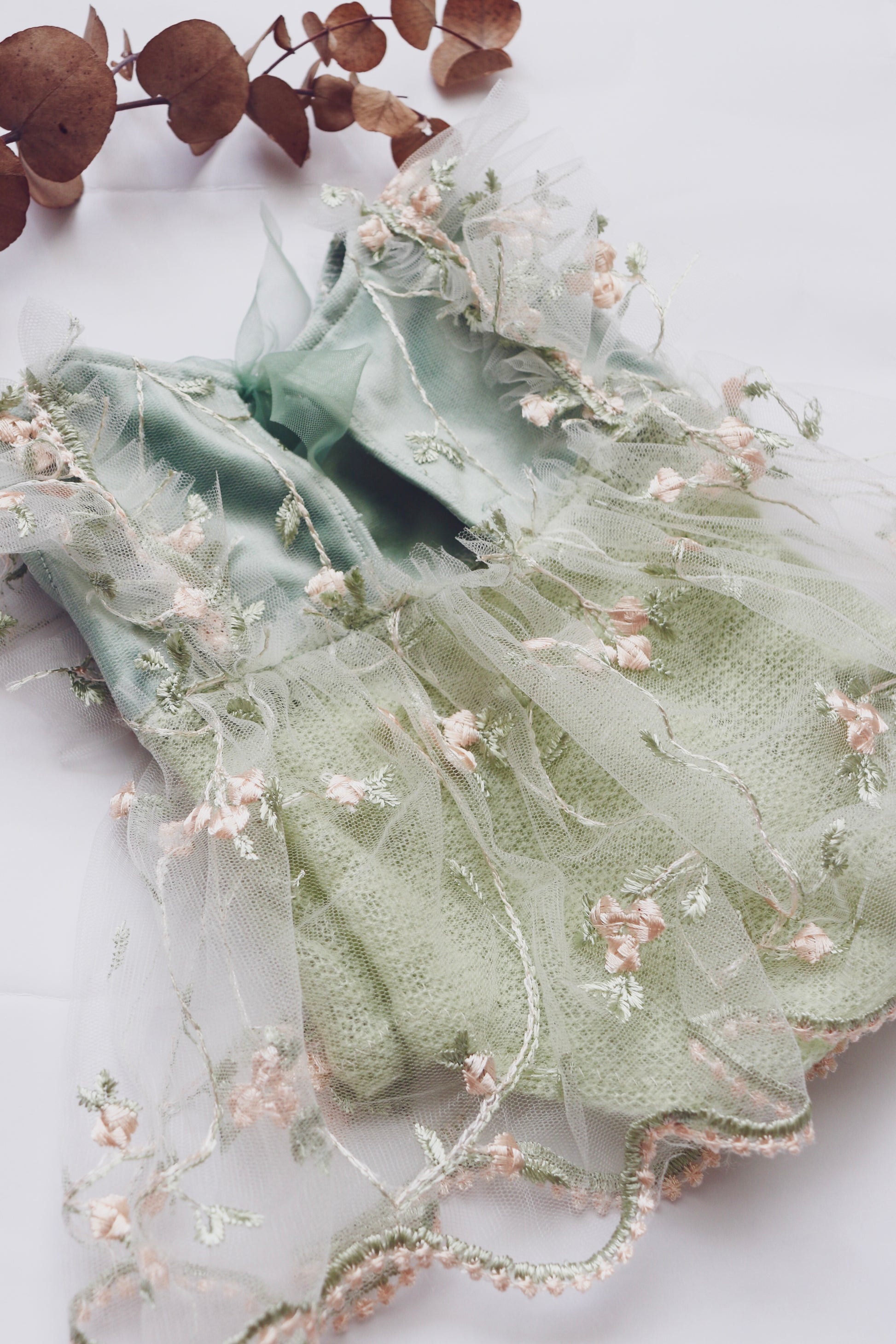 Elegant newborn dress with floral embroidery in soft green and delicate tulle details
