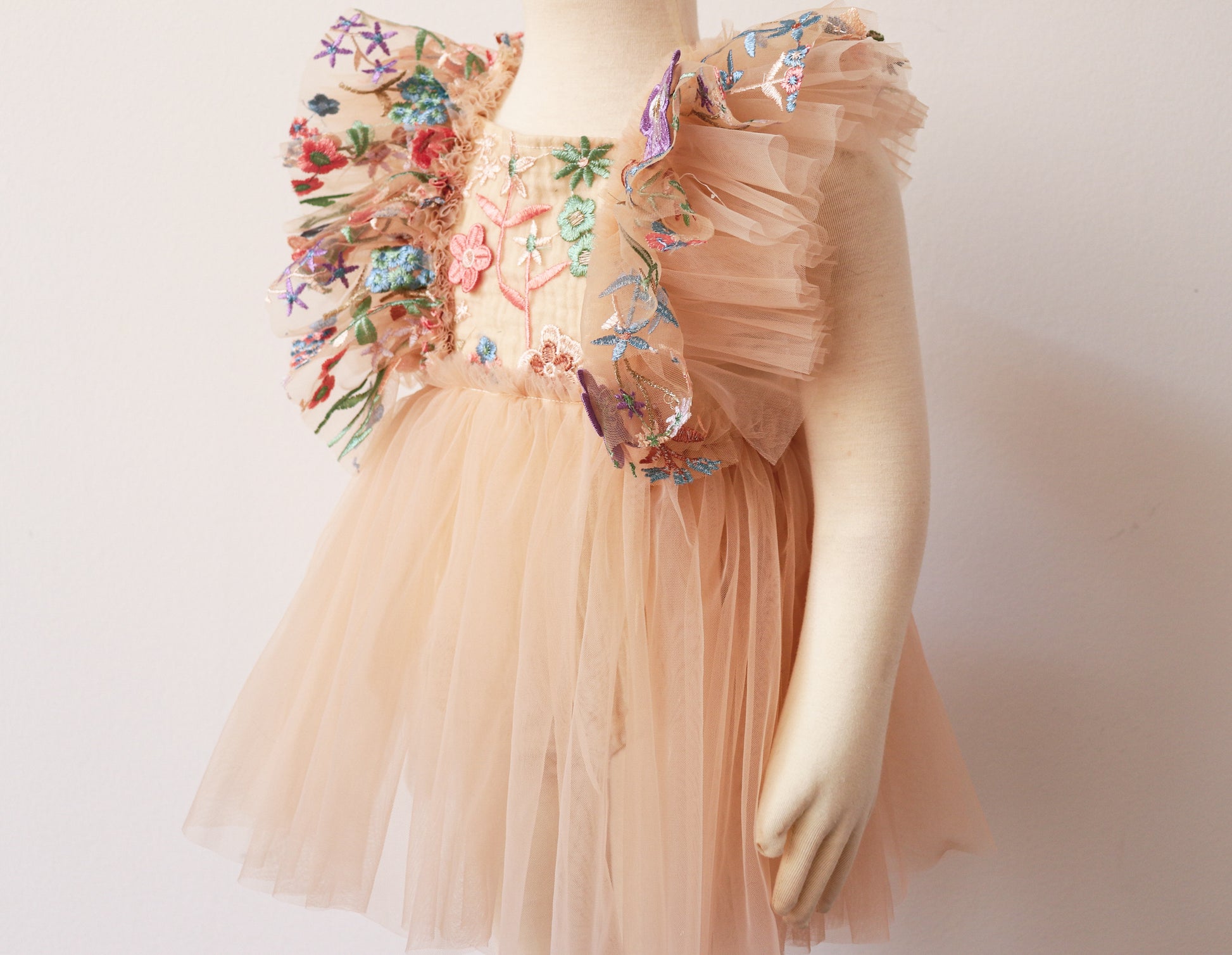 Infant portrait session clothing by FLEUR MARGOT featuring a peach tulle dress with colorful floral embroidery and ruffled sleeves