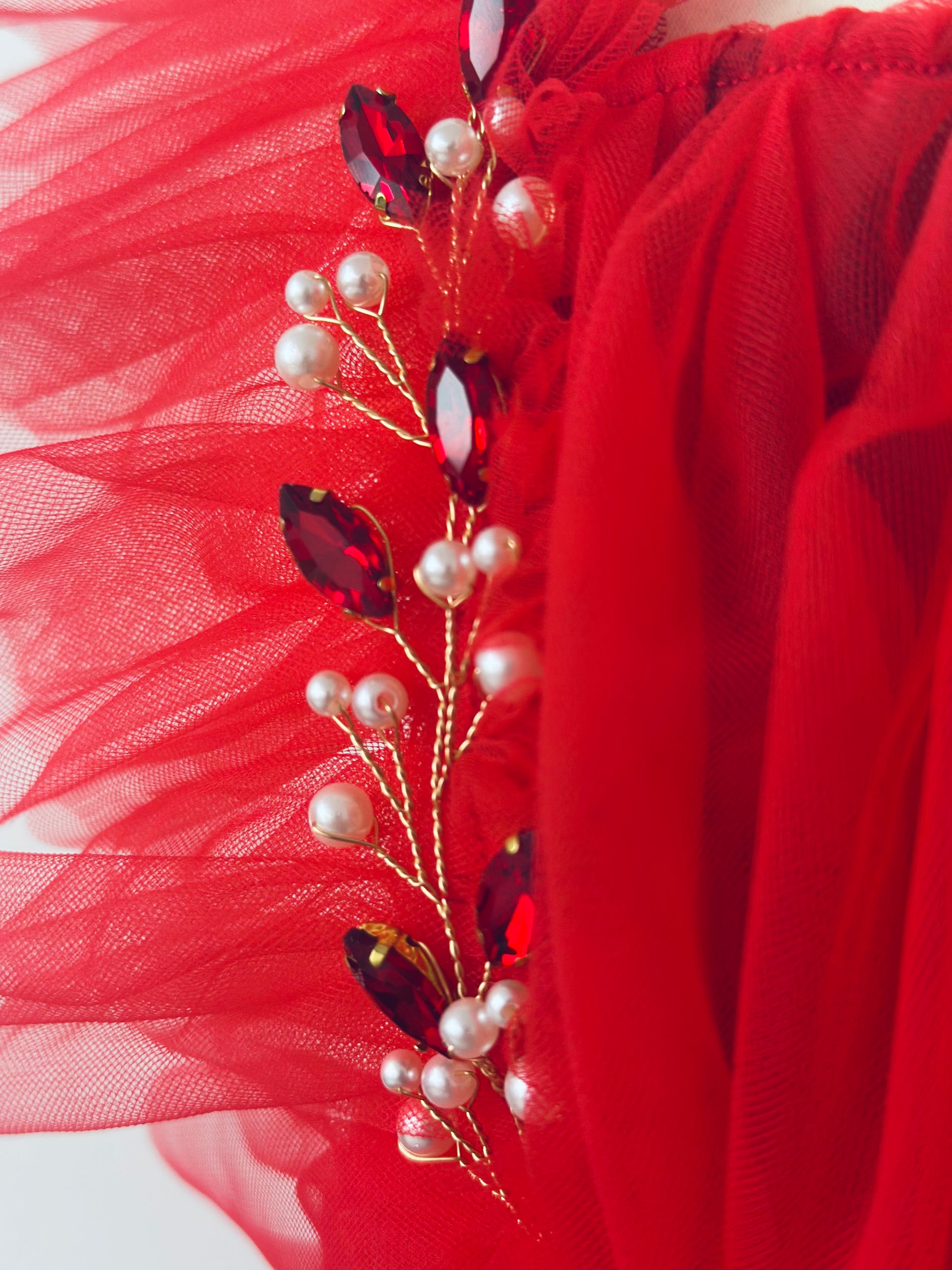 Close-up of red tulle fabric with pearls and red crystals detail in infant rhinestone Christmas outfit