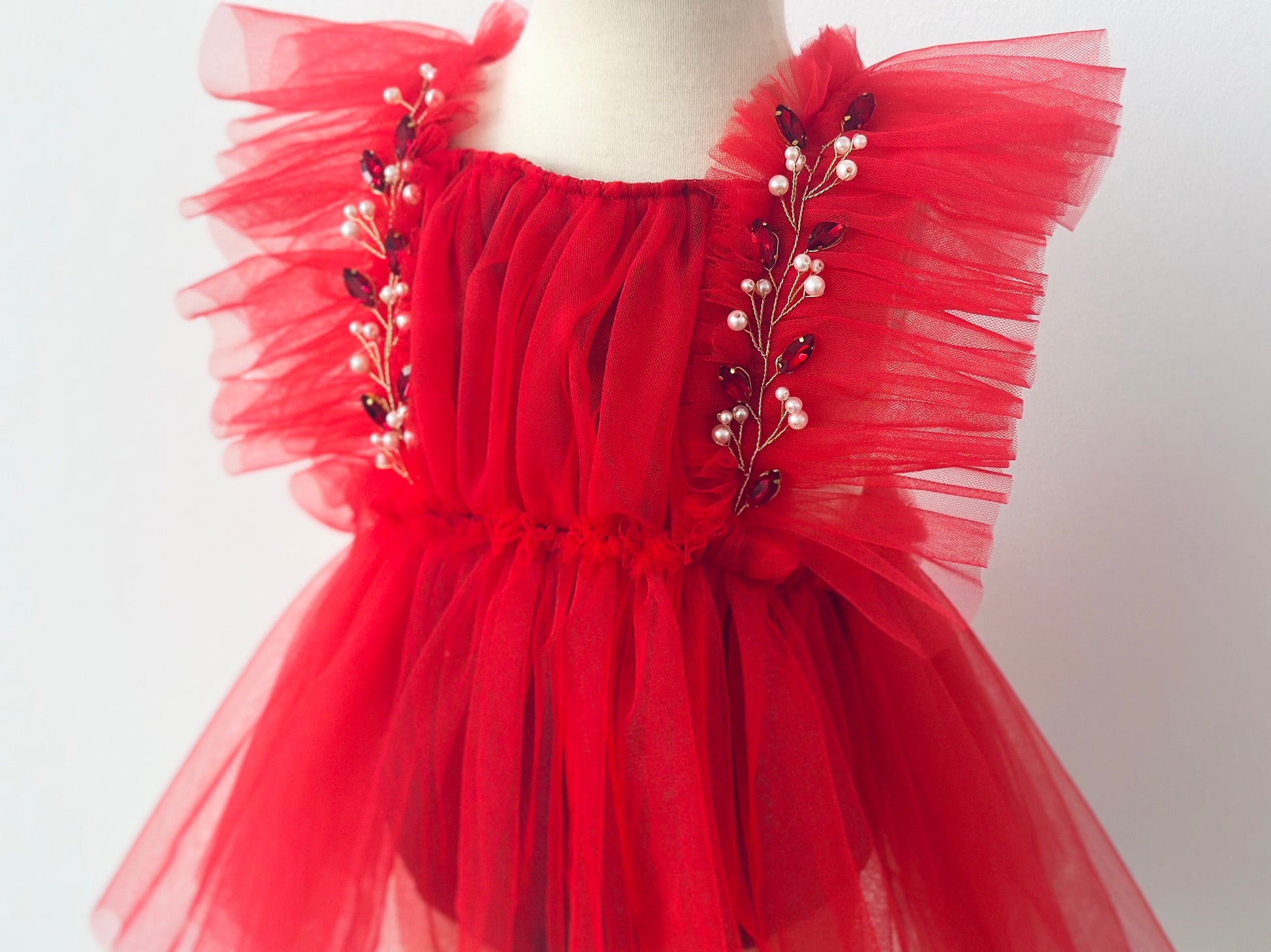 Red infant rhinestone Christmas outfit with tulle and pearl embellishments on a mannequin