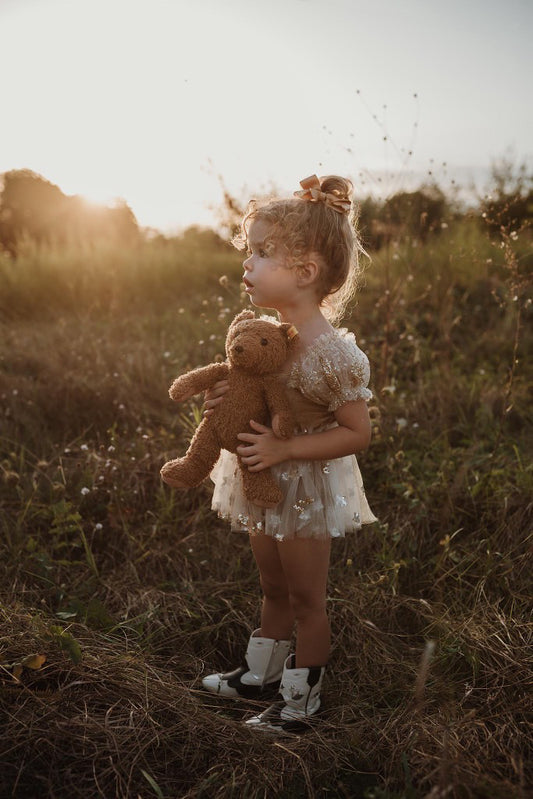 Cute photography prop dress for girls with teddy bear in a sunlit outdoor setting