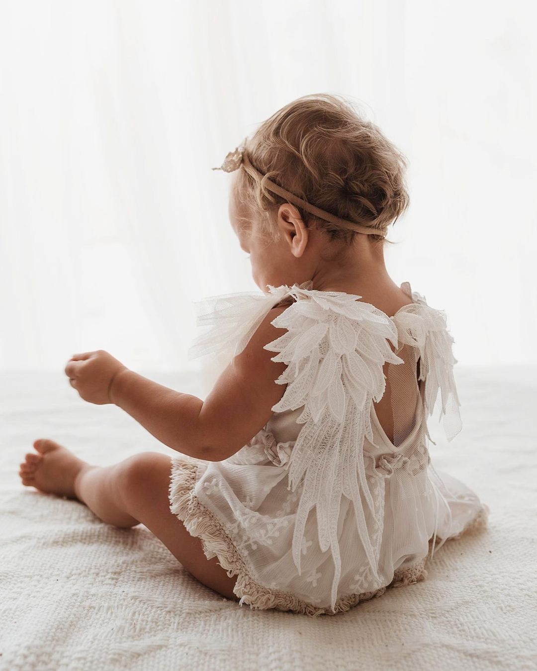 Baby girl wearing white lace romper with angel wings for sitter session photography clothes by FLEUR MARGOT