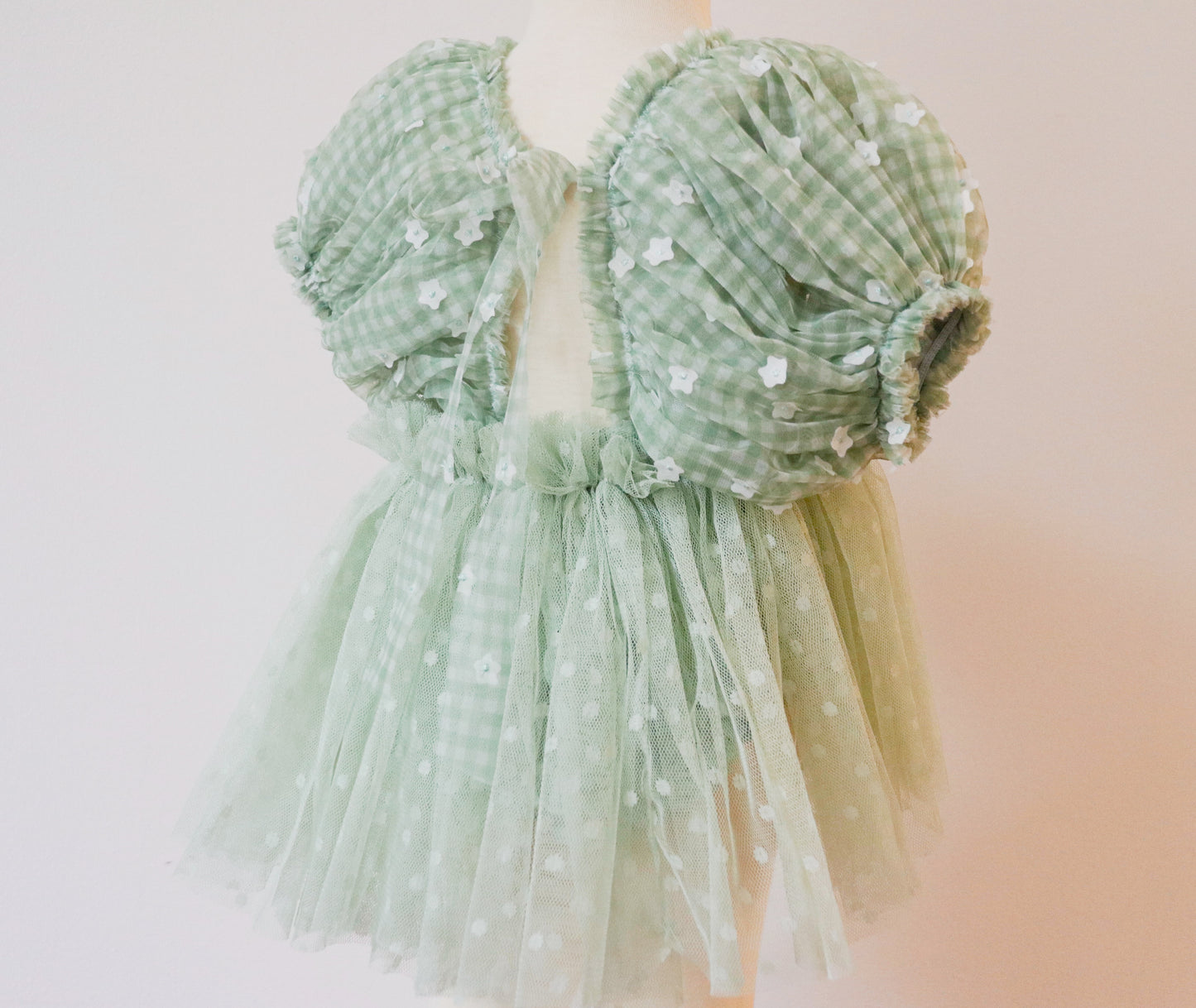 A beautiful soft green pastel girls' dress with white floral details on the puffy sleeves, perfect for birthday parties and magical outdoor moments."

