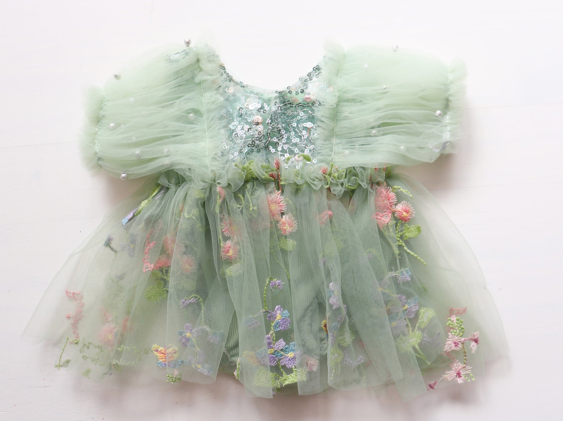 Newborn girl’s romper dress with puffy sage green tulle sleeves, colorful sequin bodice, and matching pantie