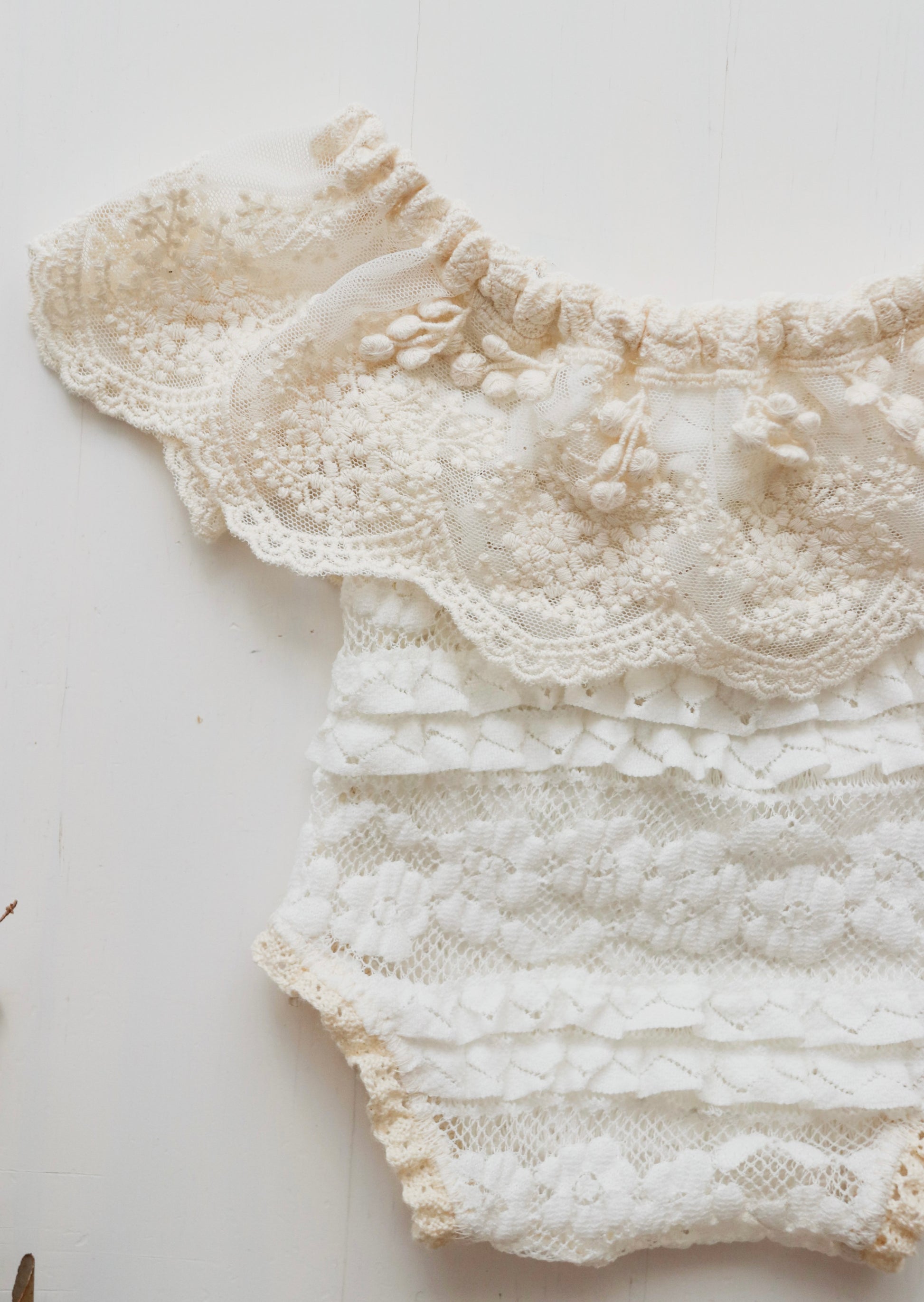 Elegant newborn girl romper with lace and ruffle details, ideal for newborn photoshoots, combining comfort and style.