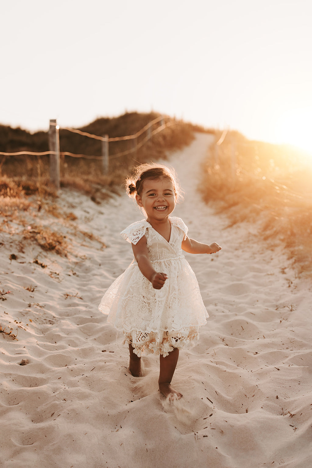 Girl’s boho dress featuring a cross-over bodice and vintage lace, perfect for outdoor sessions