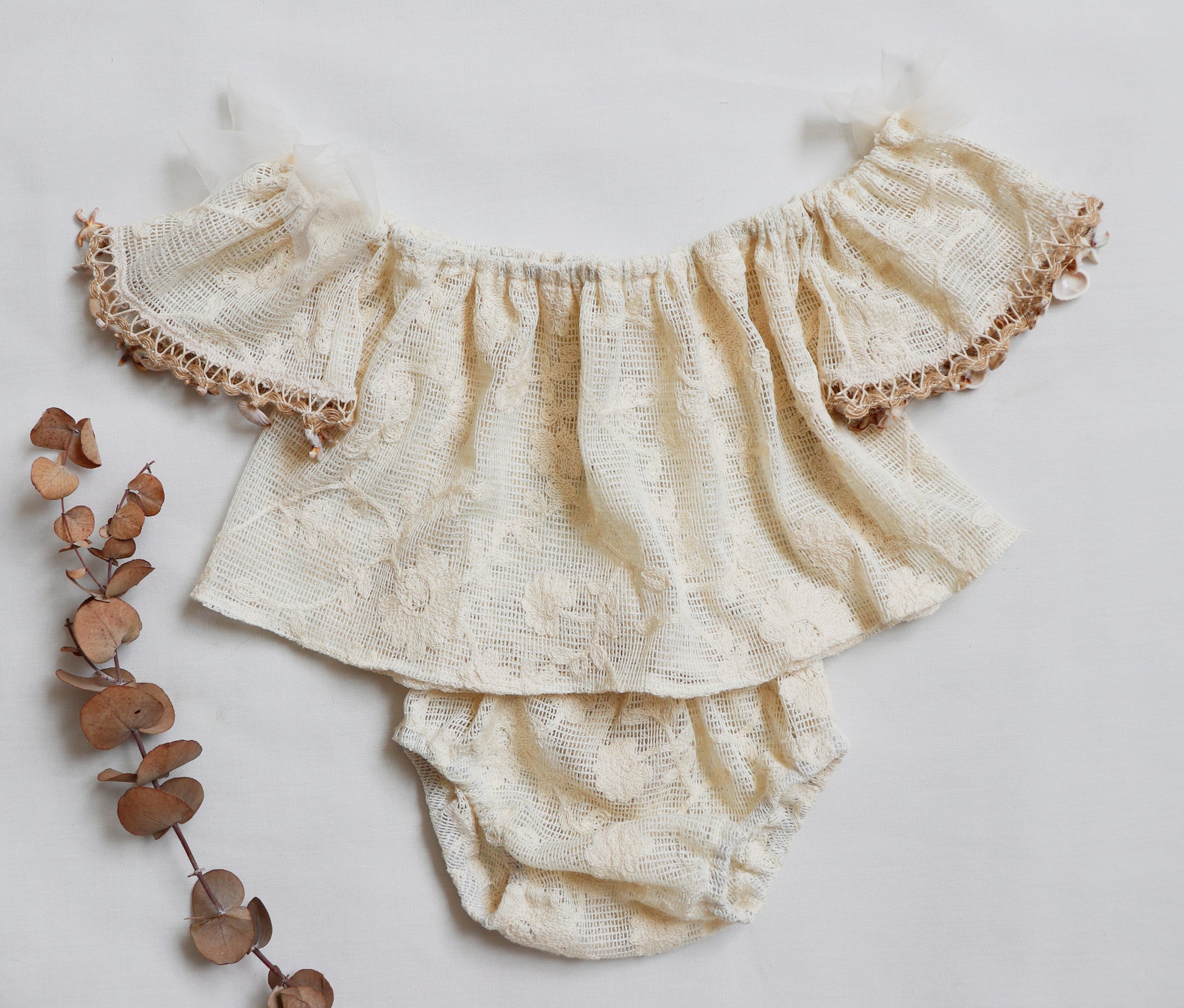 Baby girl wearing off-shoulder boho flutter top with vintage lace and shell trim, paired with matching bloomer

