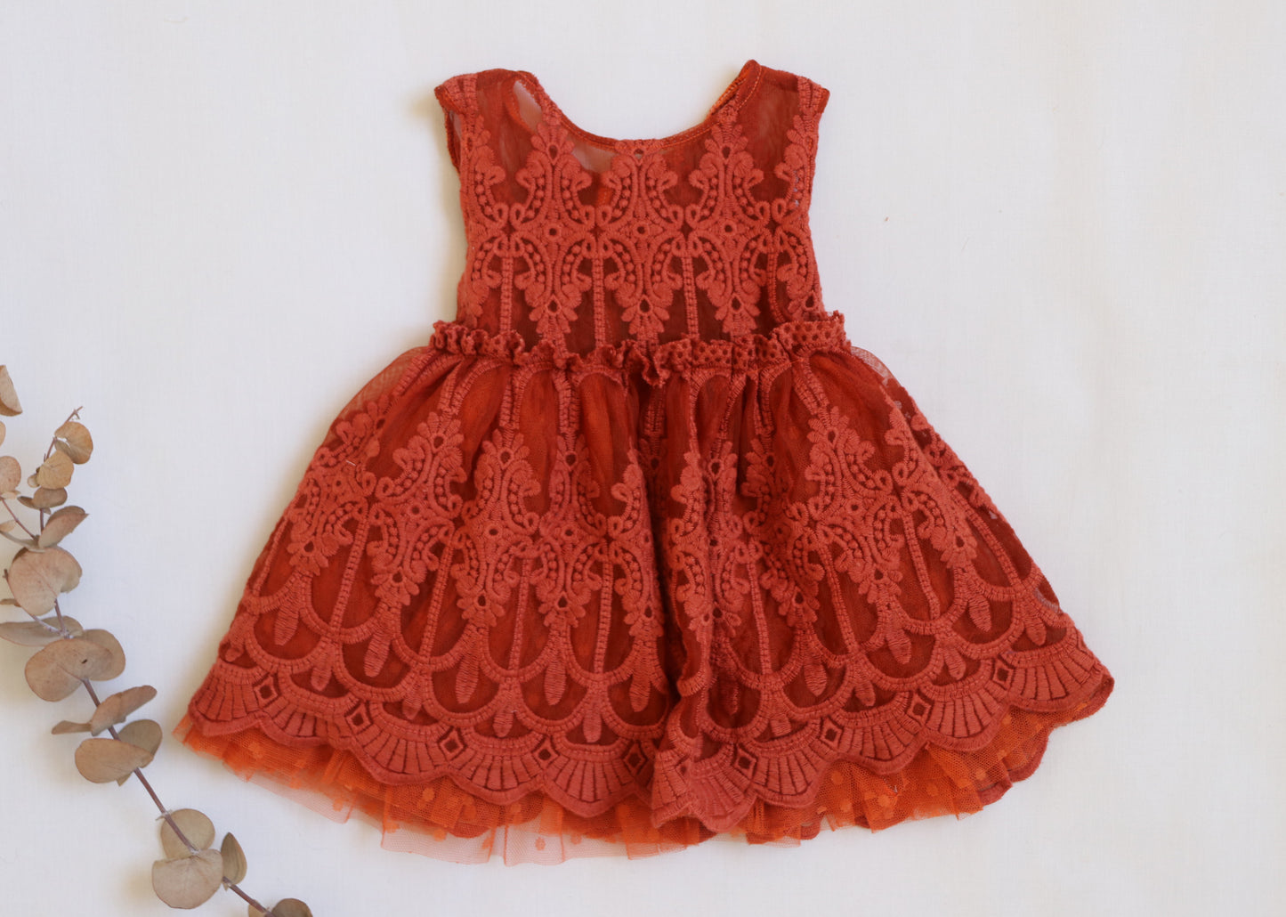"Girl in a terracotta boho dress with vintage lace and embroidered flowers, styled with a velvet bloomer for a rustic outdoor session."

