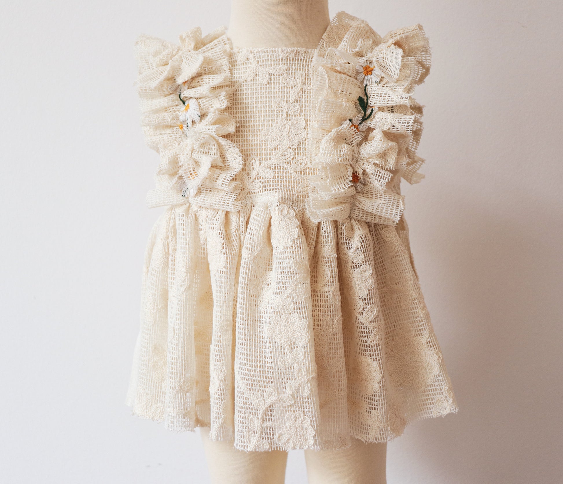 "Boho baby dress with vintage lace, soft ruffles, four mini ribbon bows, and daisy flowers, paired with a matching bloomer – perfect for dreamy outdoor photoshoots."

