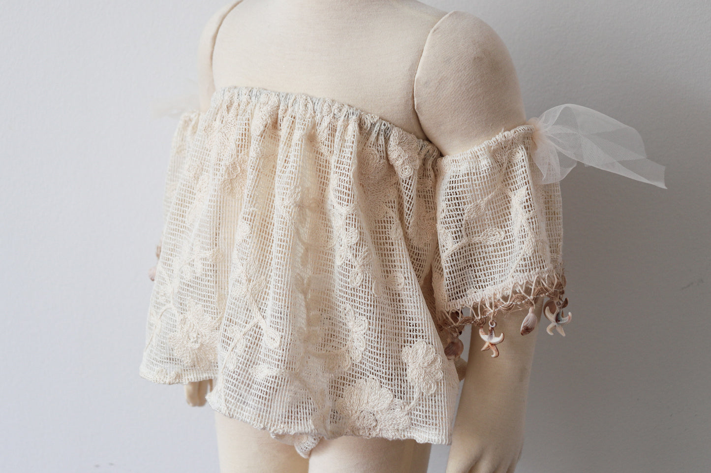 Little girl at an outdoor photoshoot wearing vintage-style boho top and bloomer set with natural shell accents

