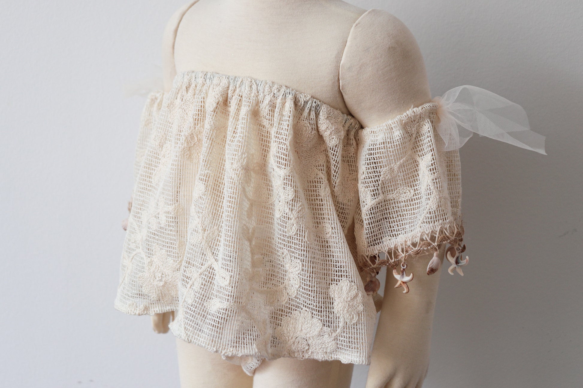 Little girl at an outdoor photoshoot wearing vintage-style boho top and bloomer set with natural shell accents

