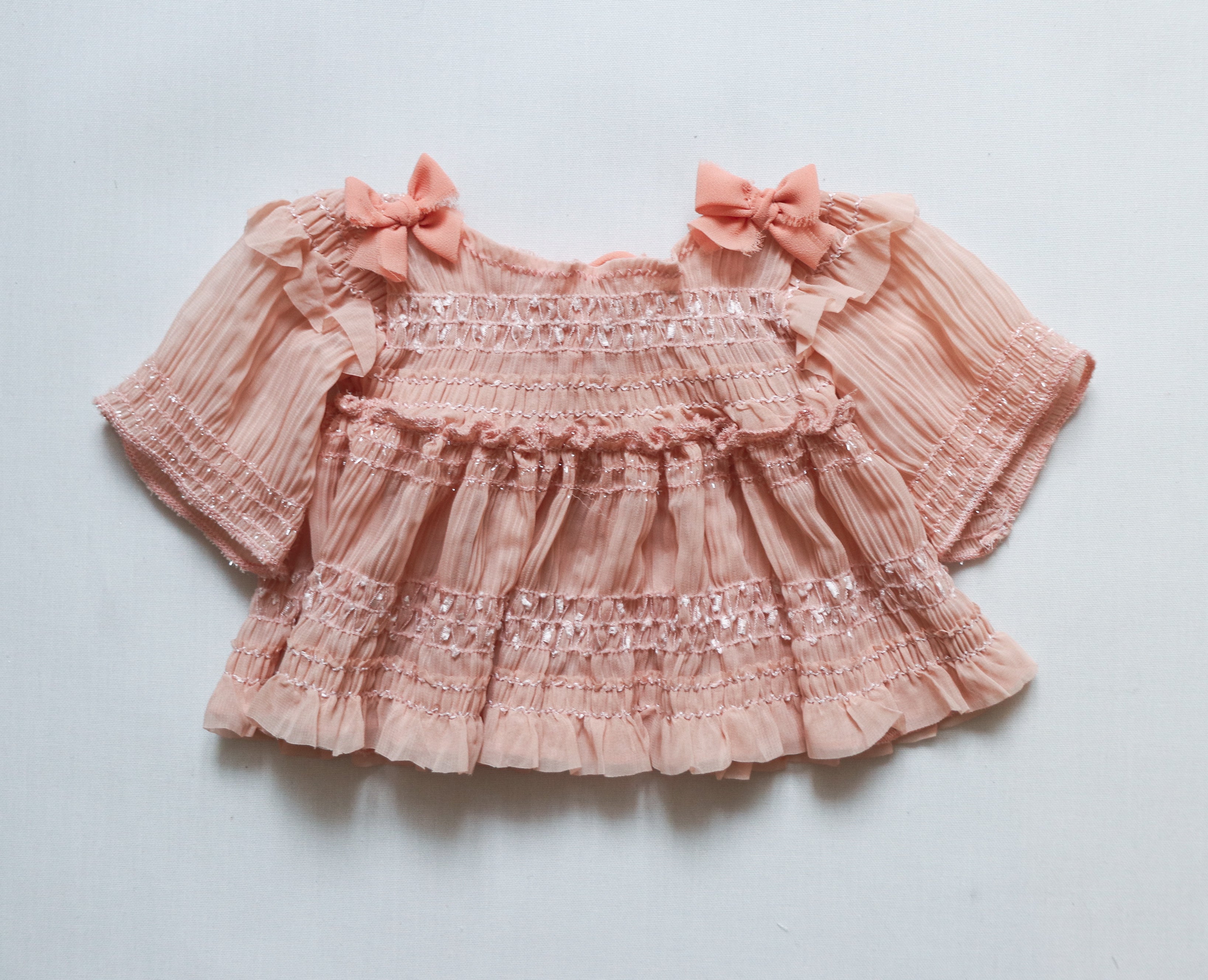  Newborn girl dress in soft dust pink wrinkled chiffon fabric, featuring long sleeves, a matching diaper cover, and two small bows on the bodice, perfect for photoshoots or newborn sessions.