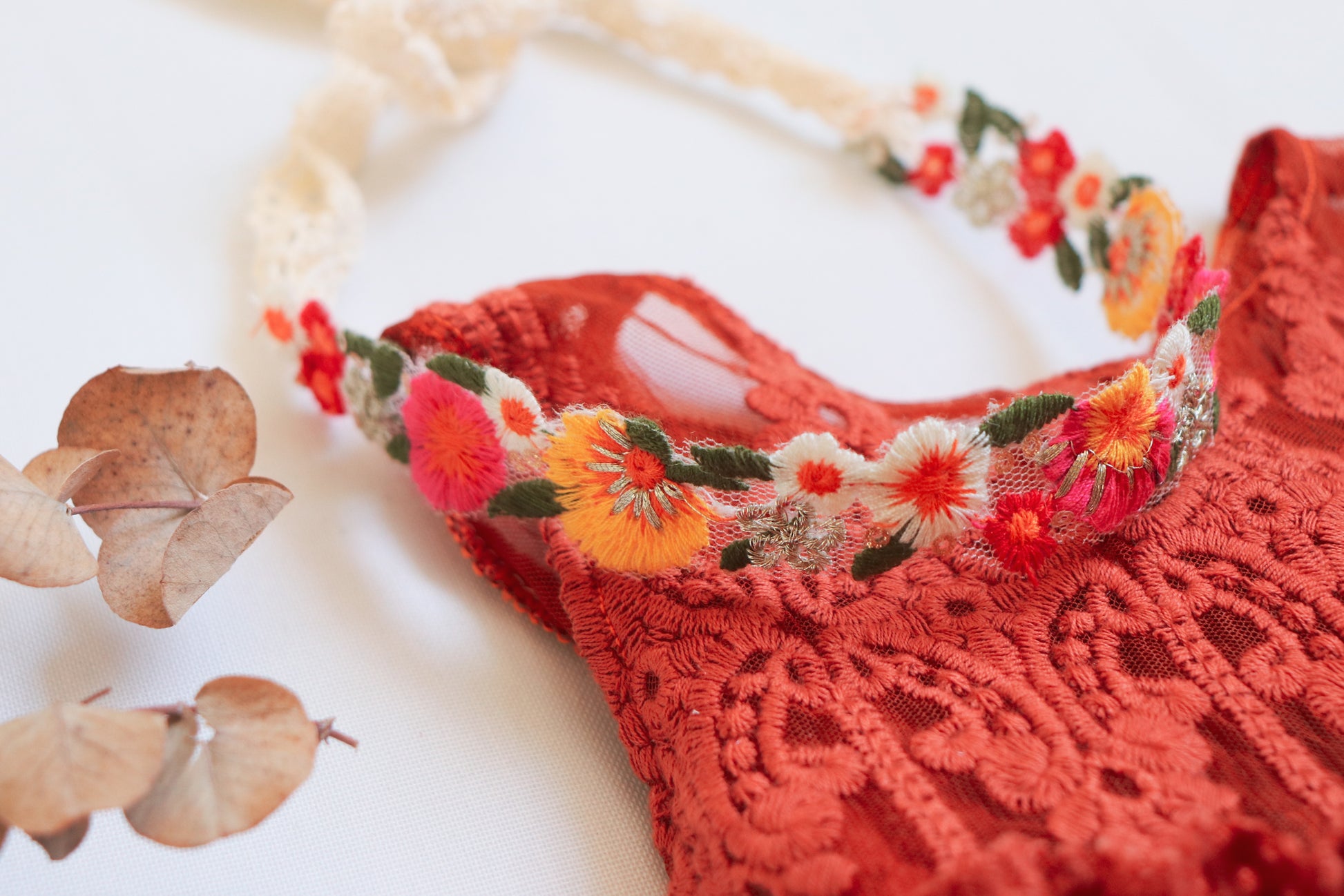 "Close-up of embroidered floral details on a sleeveless terracotta dress with matching velvet bloomer, captured during a golden hour session."

