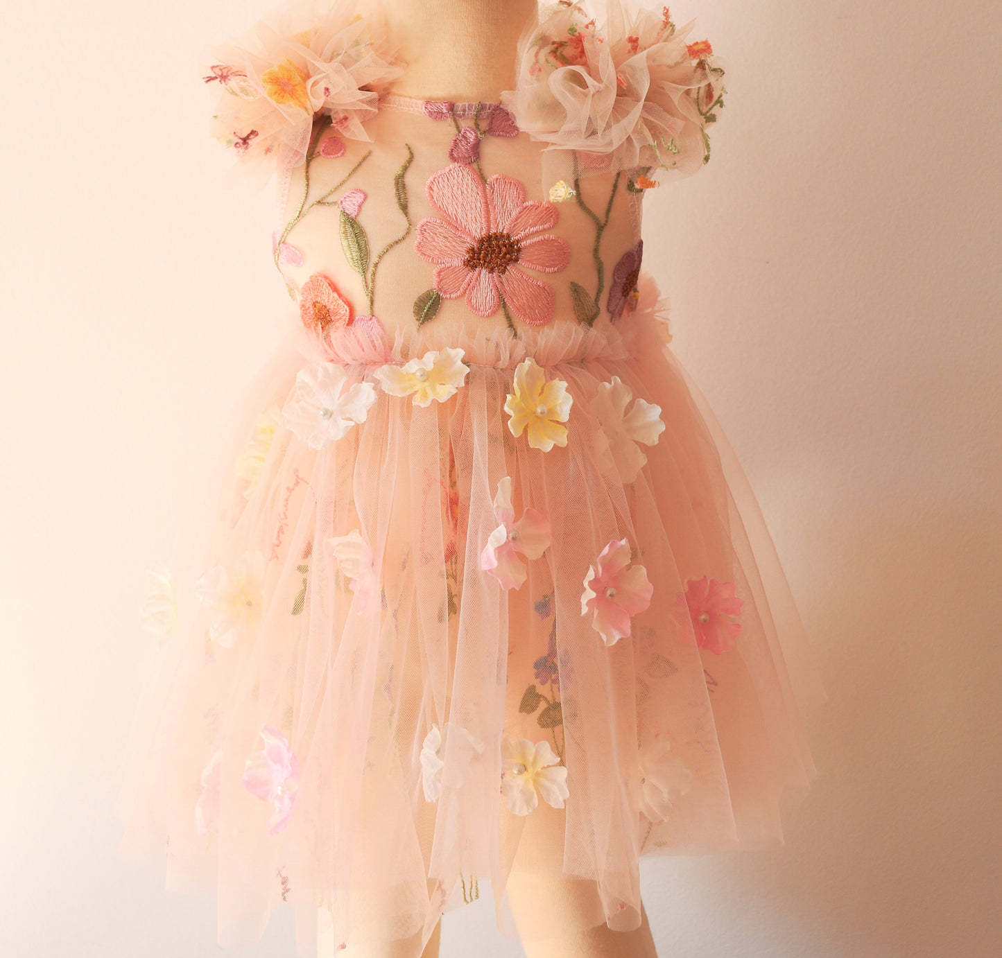 Little girl twirling outdoors in a sleeveless pink tulle dress with 3D floral appliqués, perfect for spring birthday photos.

