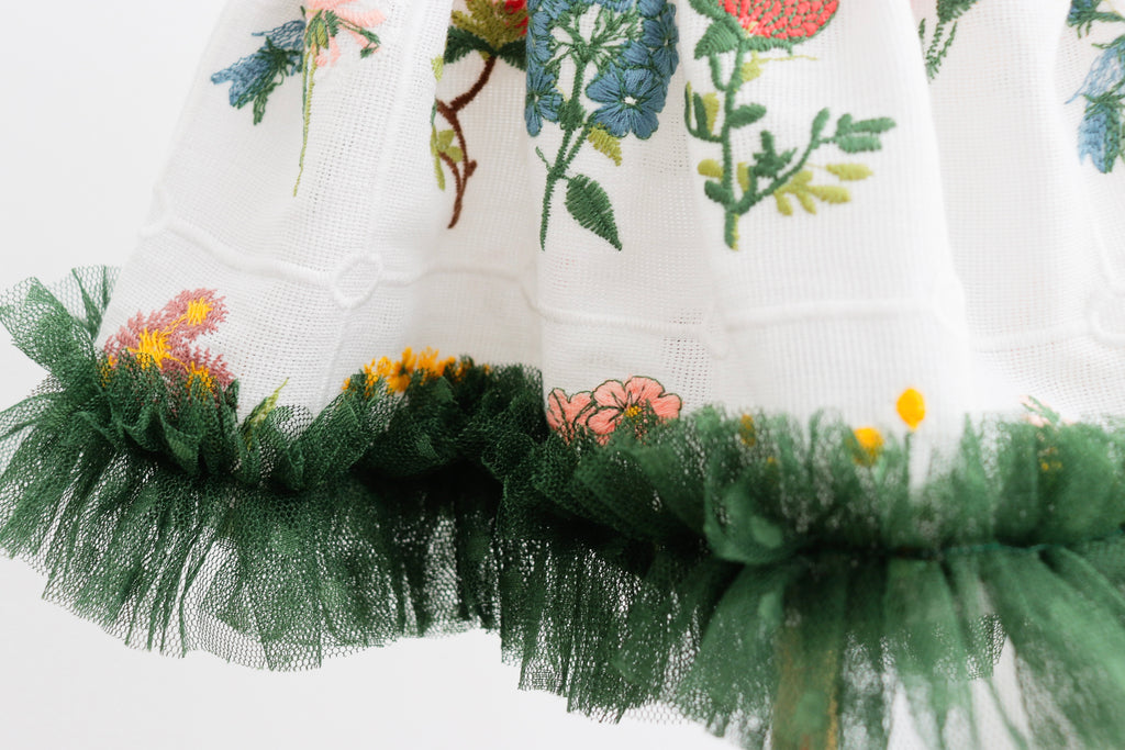 "Close-up of floral embroidery and soft green tulle on newborn girl dress"

