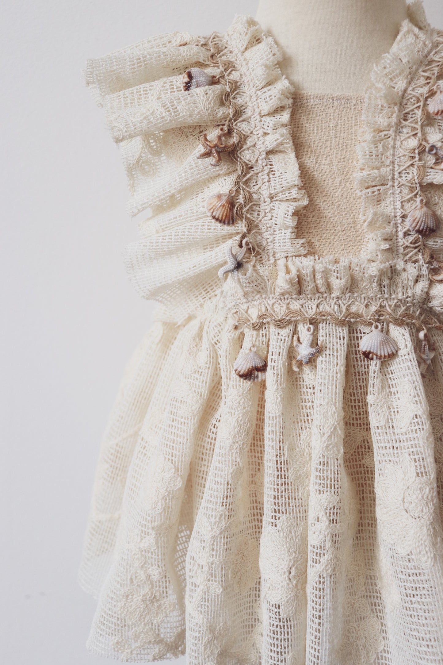 A beautifully crafted girls' boho dress with ruffled lace details, crossed adjustable straps, and seashell fringe, designed for bohemian photo sessions and special occasions.