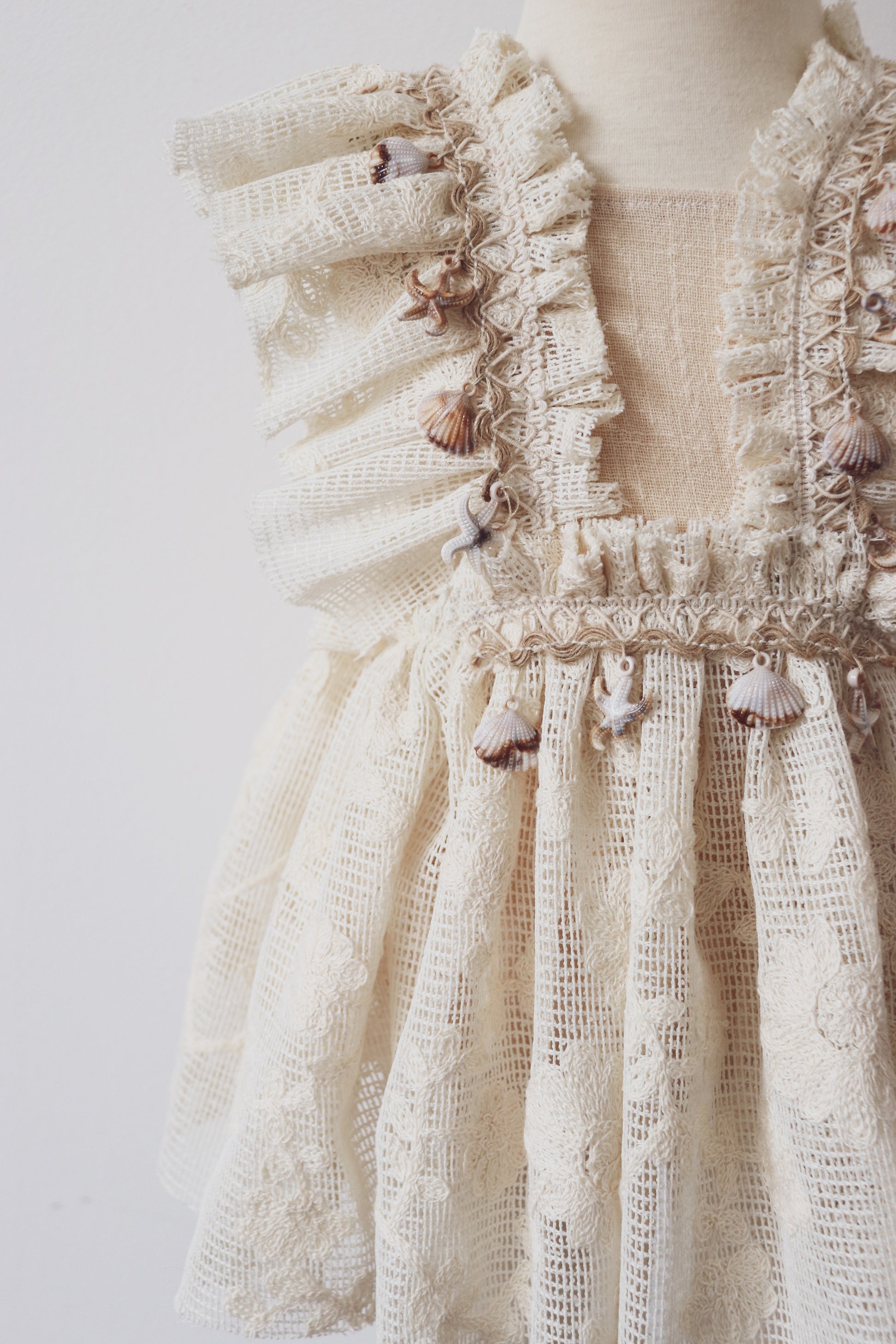 A beautifully crafted girls' boho dress with ruffled lace details, crossed adjustable straps, and seashell fringe, designed for bohemian photo sessions and special occasions.