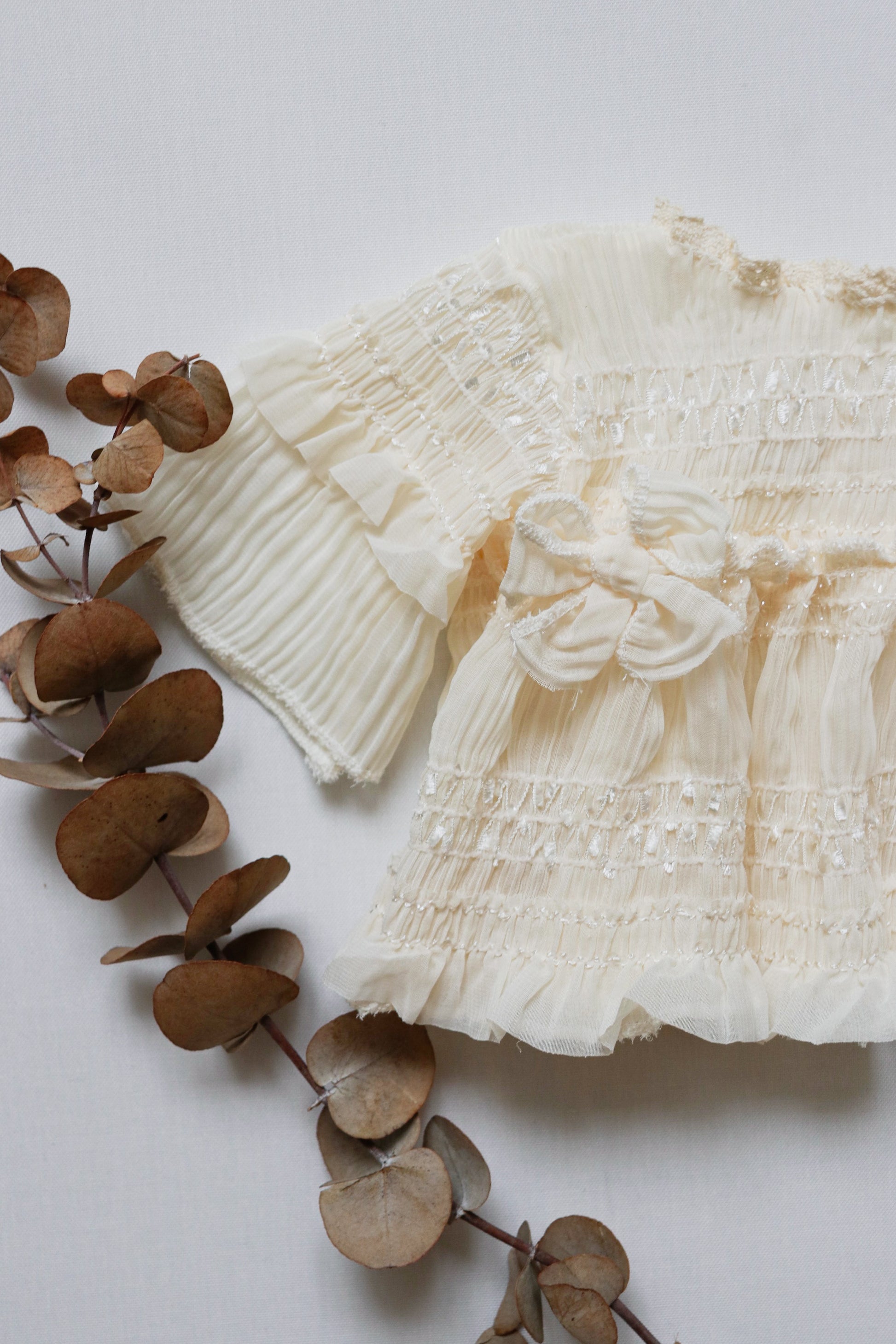  "Ivory newborn dress made from wrinkled chiffon, designed with long sleeves, two dainty bows on the bodice, and a matching diaper cover for timeless newborn photography."