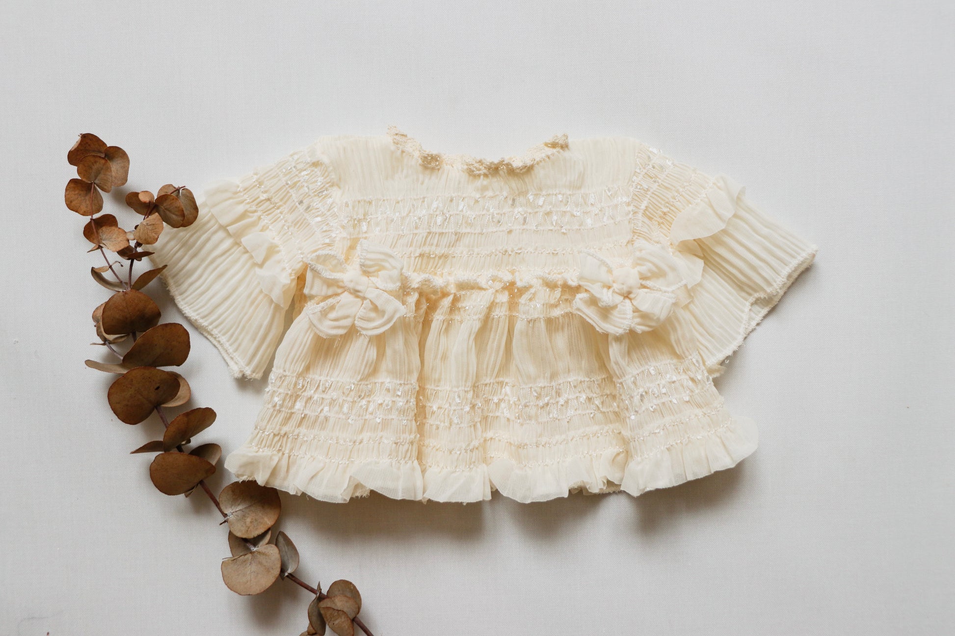 Newborn girl dress in soft ivory wrinkled chiffon fabric, featuring long sleeves, a matching diaper cover, and two delicate bows on the bodice, perfect for photoshoots and newborn sessions."