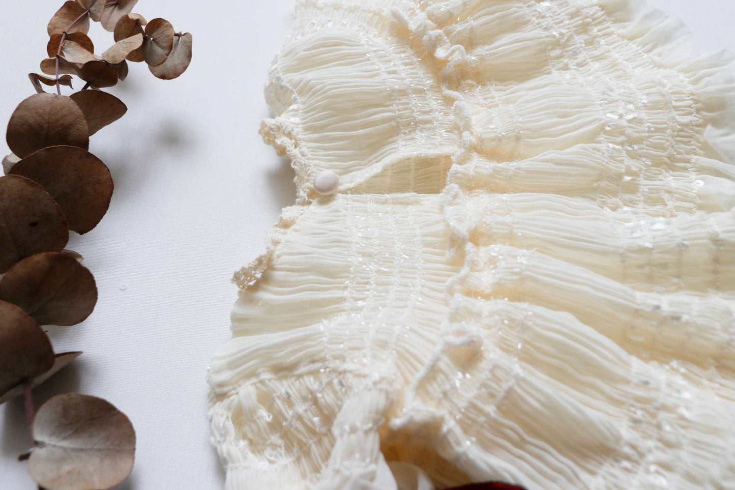 "Charming ivory newborn girl dress in wrinkled chiffon with long sleeves, two small bows on the bodice, and a coordinating diaper cover, perfect for professional photoshoots and special occasions."