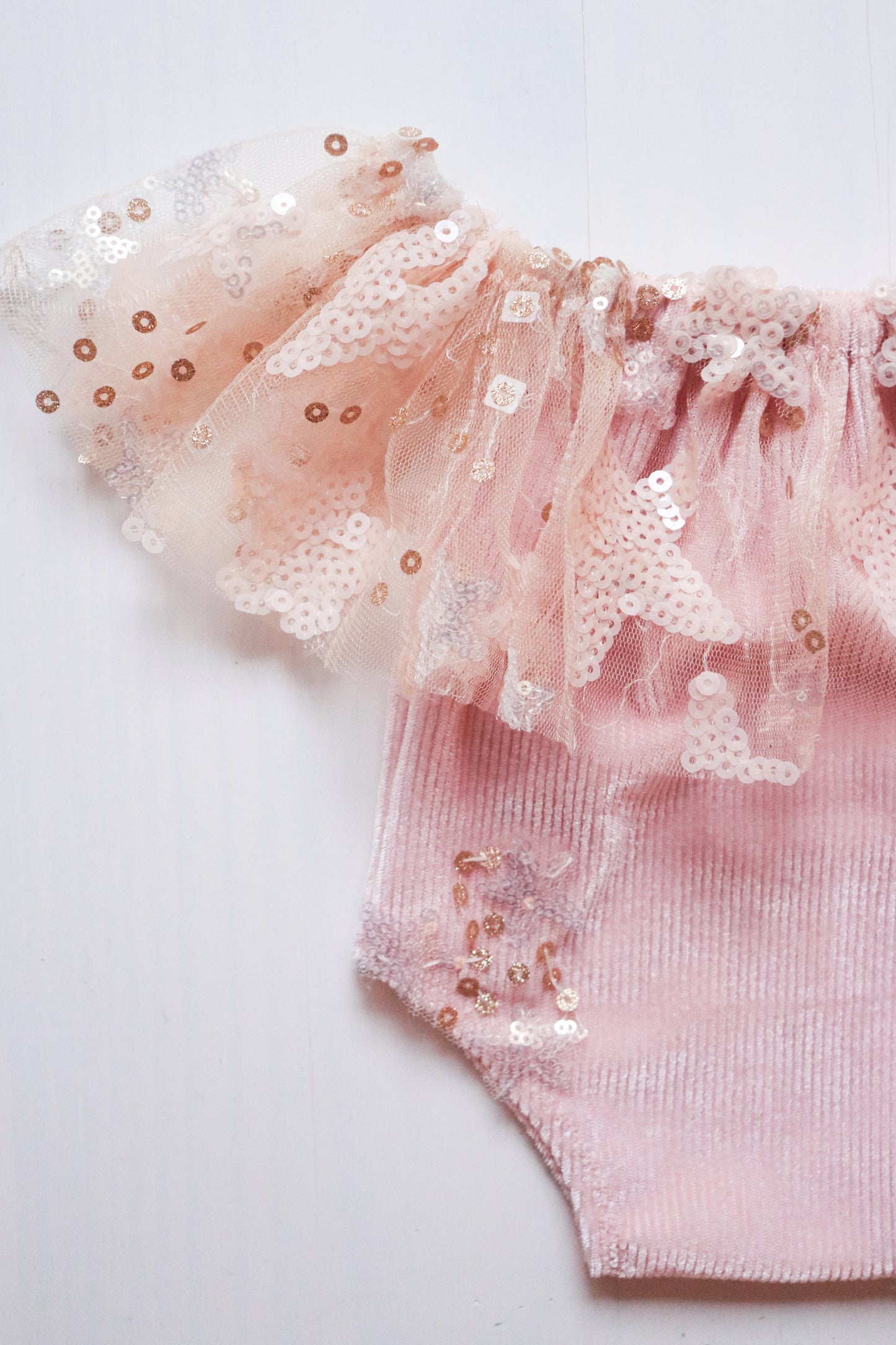 Newborn girl romper featuring pink, silver, and golden star-shaped sequins on the ruffled neck