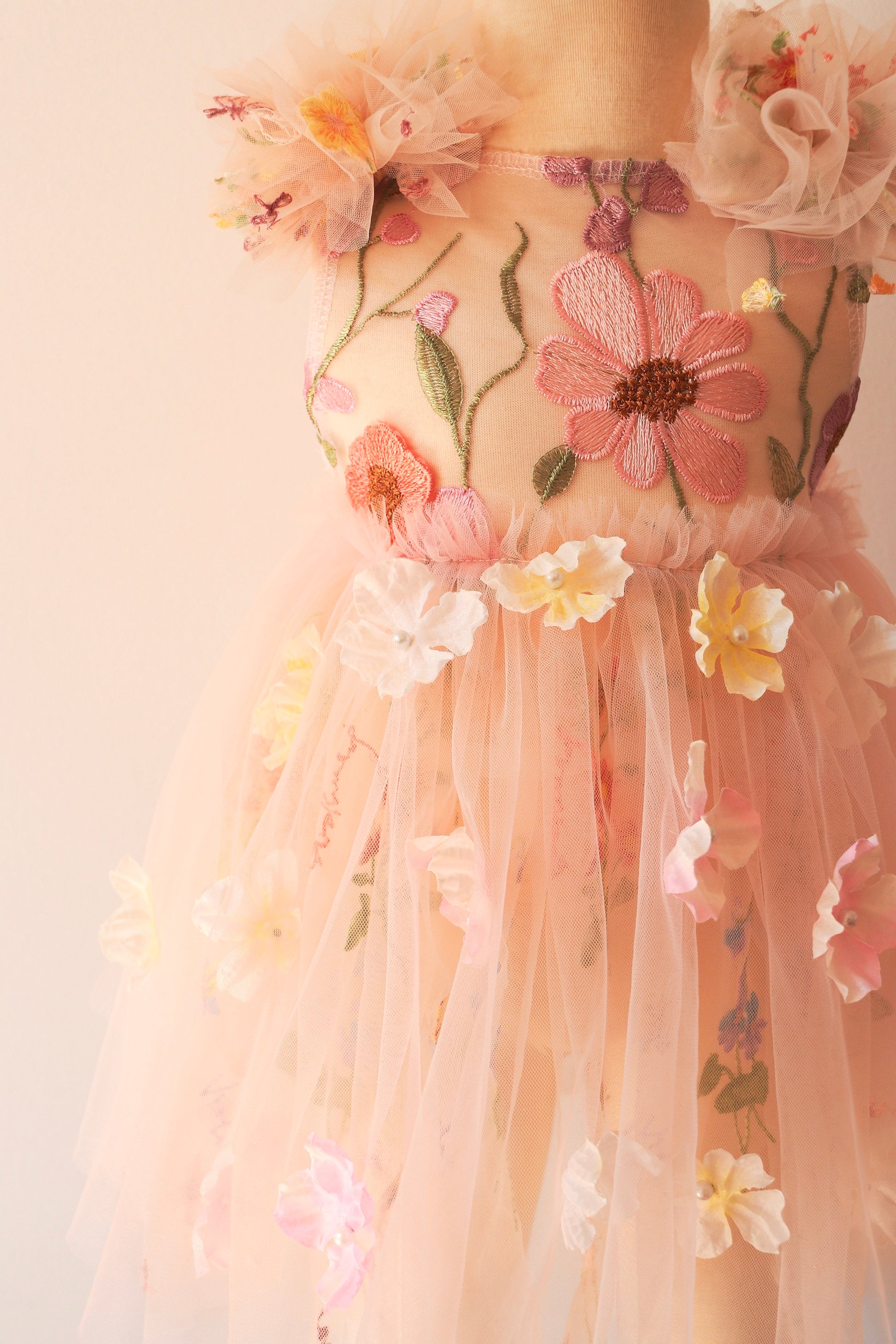 Girl wearing a sleeveless pink dress with embroidered bodice and 3D flowers, captured during a dreamy outdoor birthday photoshoot.

