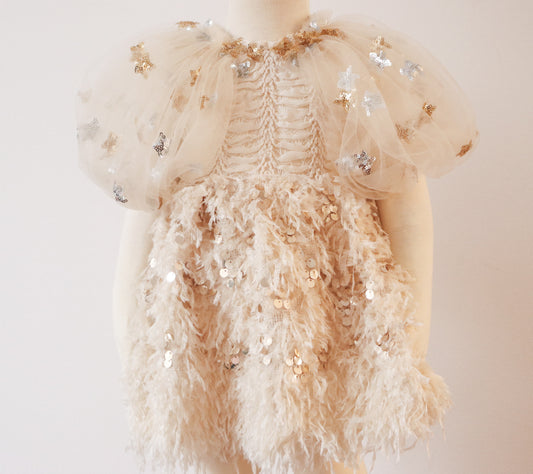 Bring timeless elegance to your child’s photoshoots with this Rococo-inspired girl’s dress. Featuring puffy tulle sleeves adorned with shimmering star sequins, an intricately embroidered fish bone chest, and a flowing light beige feather skirt with gold accents, this dress is perfect for special occasions