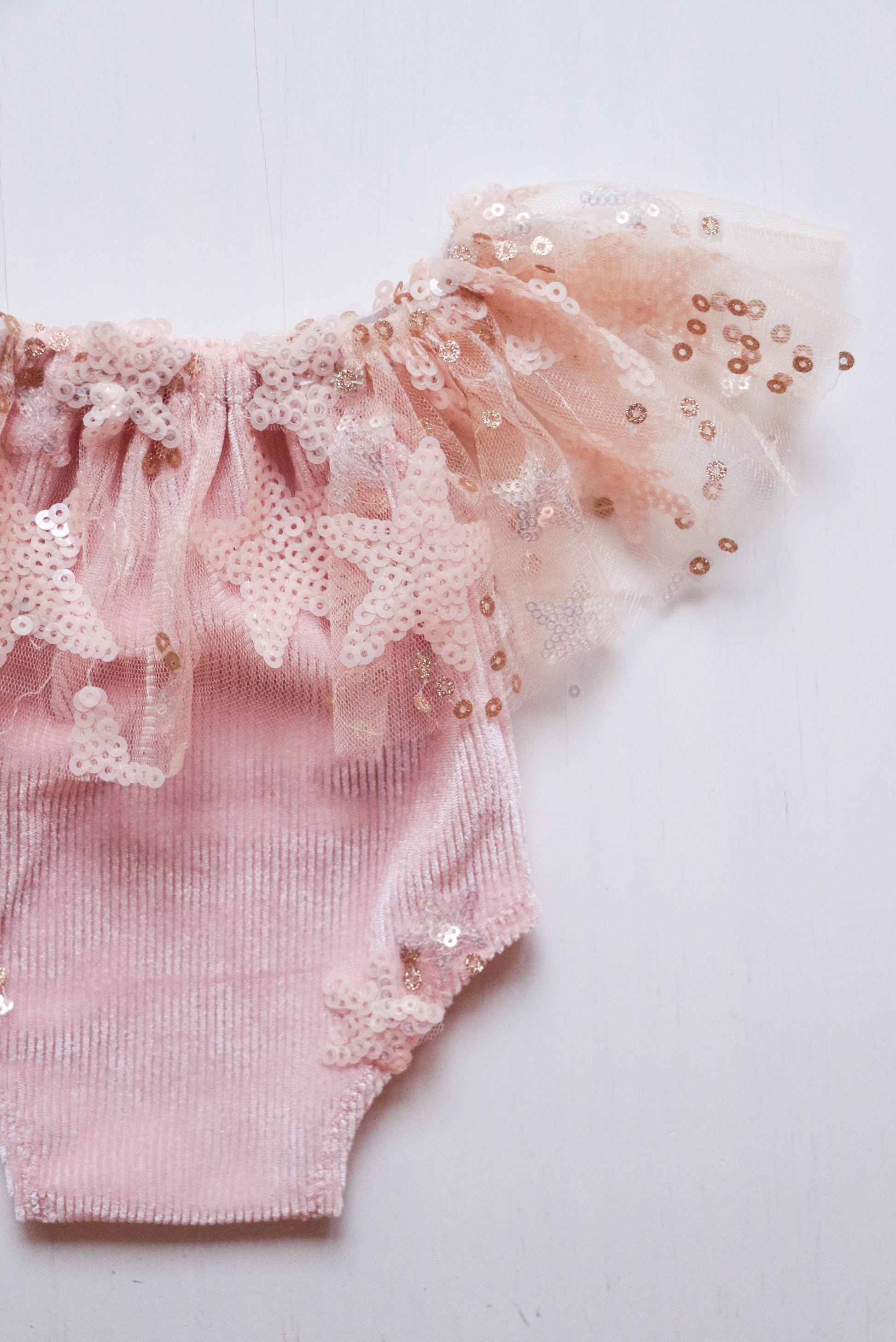 Baby pink romper with ruffled neck and star-shaped sequins, designed for stylish newborn photoshoots