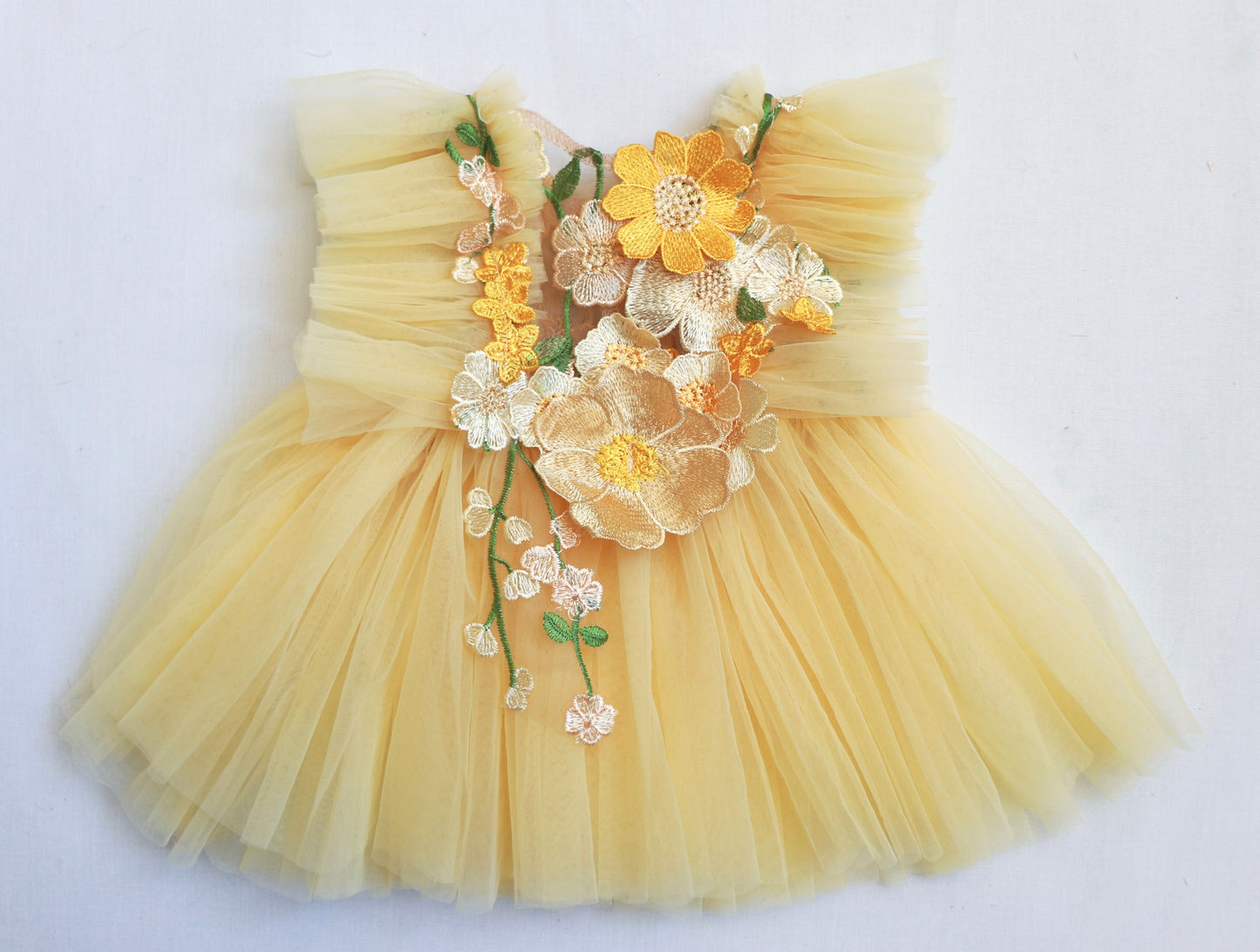 "Toddler wearing a soft pastel yellow dress with ruffled tulle and blooming 3D flowers, perfect for a summer celebration or Easter event."

