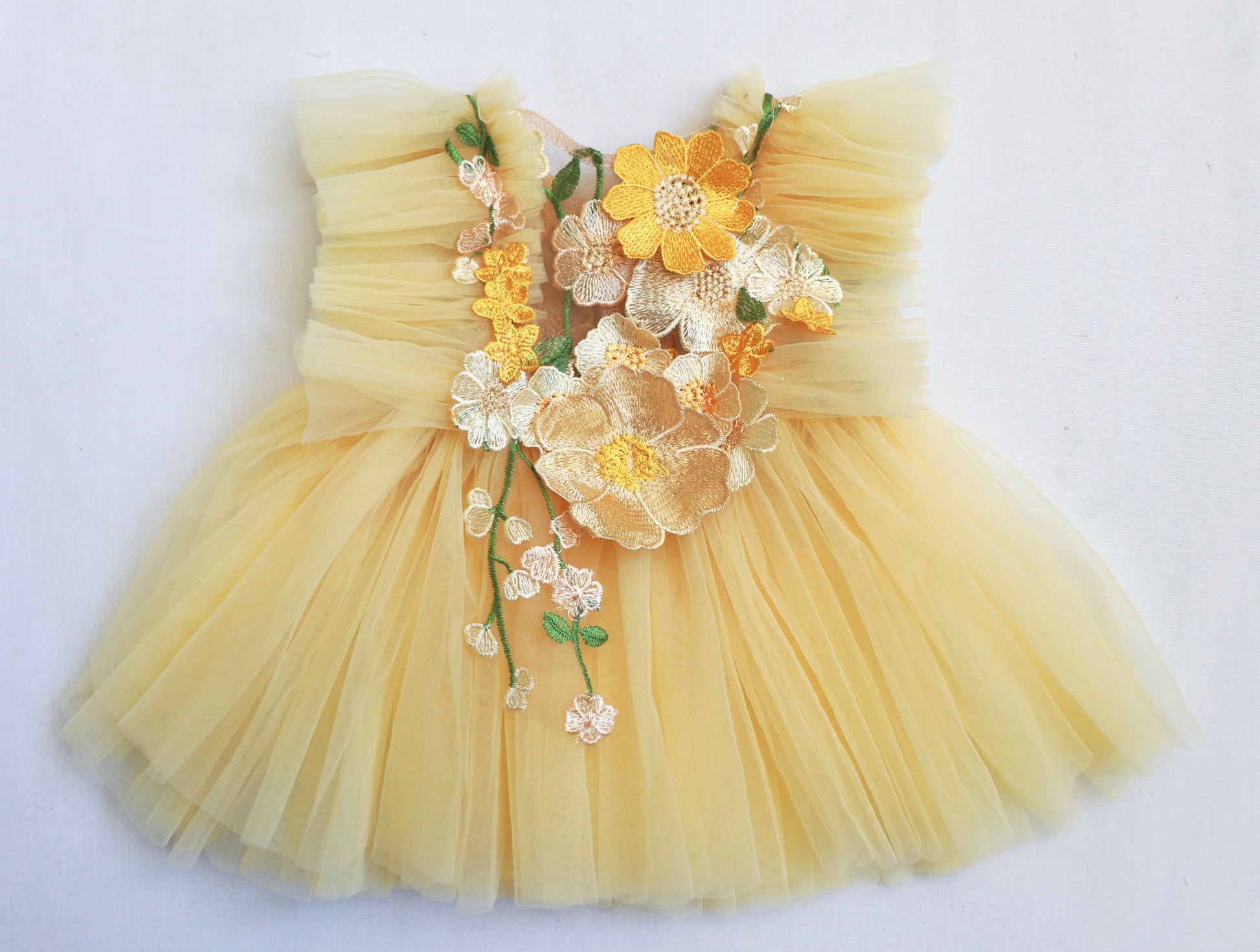 "Toddler wearing a soft pastel yellow dress with ruffled tulle and blooming 3D flowers, perfect for a summer celebration or Easter event."

