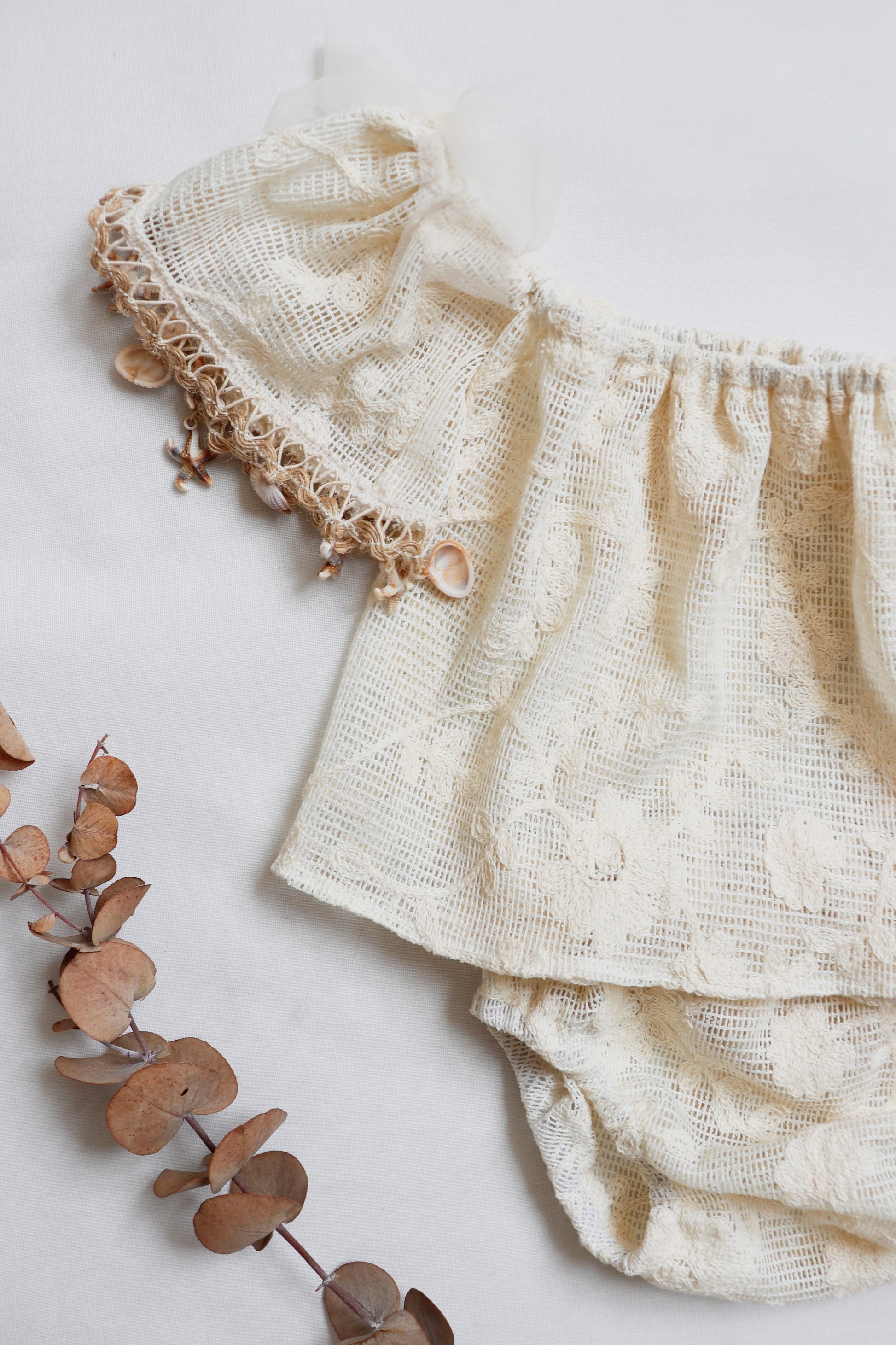 Close-up of flutter sleeves with delicate lace and shell trim on a girl's summer outfit

