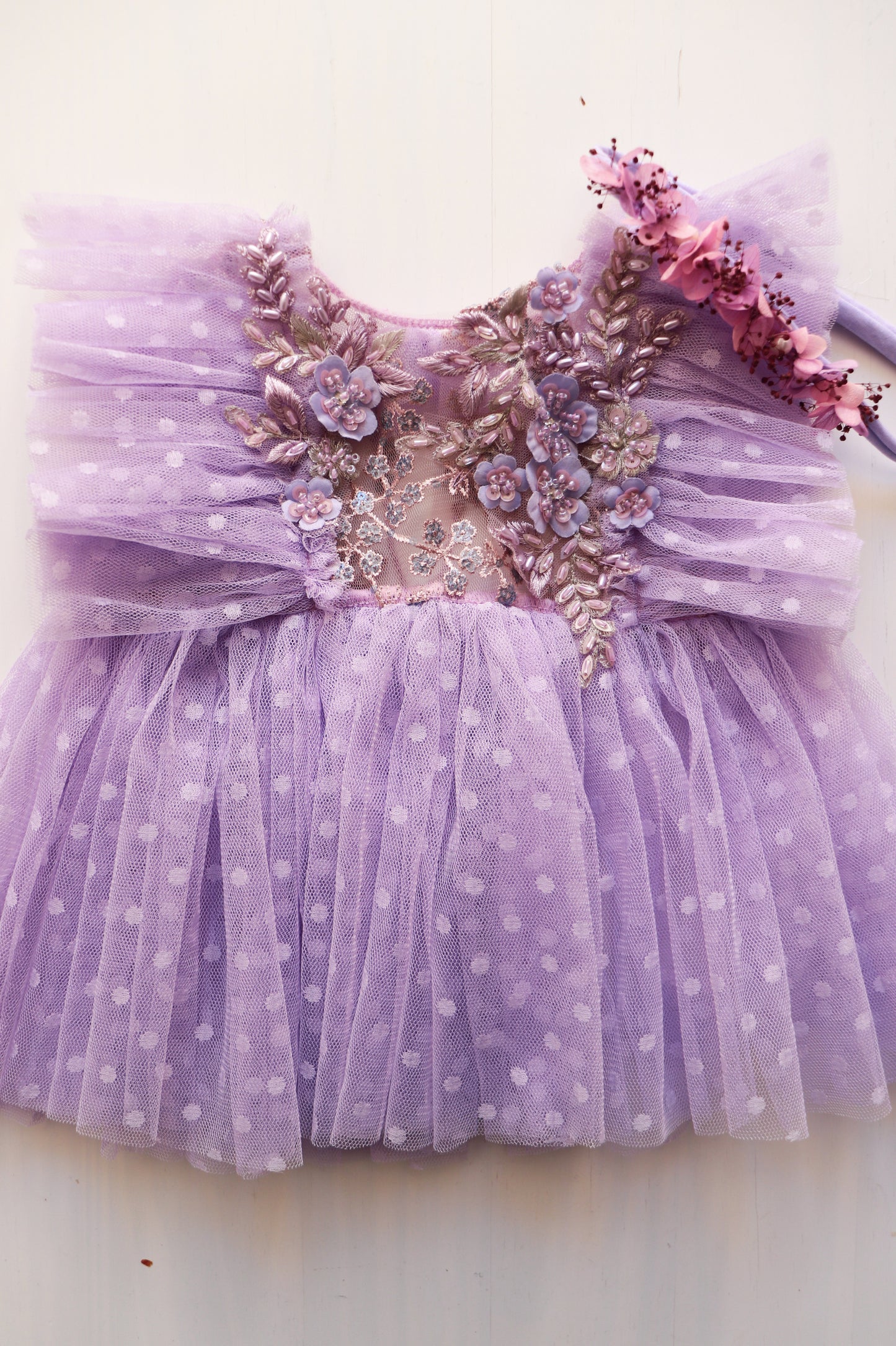 This whimsical lavender dress, adorned with dotted tulle and 3D floral details, is completed by a beautiful dried flower Hortensia tieback. A delightful outfit for birthdays, photoshoots, and cherished memories.

