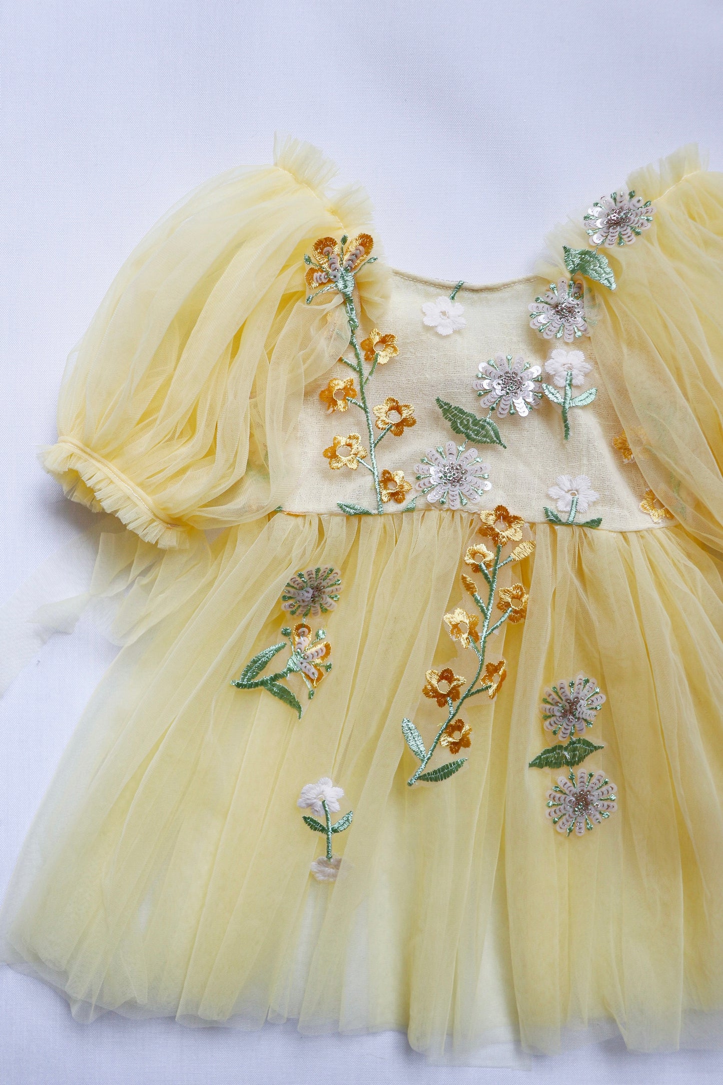 Yellow floral sitter romper dress with delicate puff sleeves and intricate flower embroidery