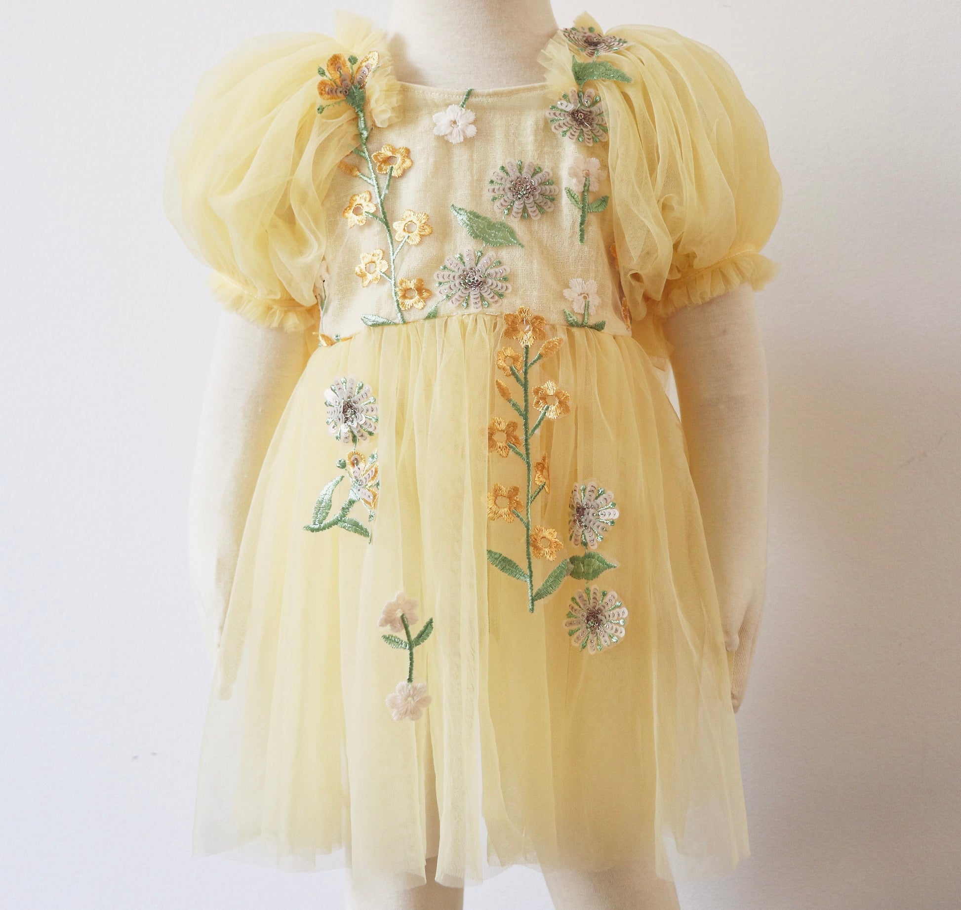 Yellow floral sitter romper dress by FLEUR MARGOT with puff sleeves and embroidered flowers